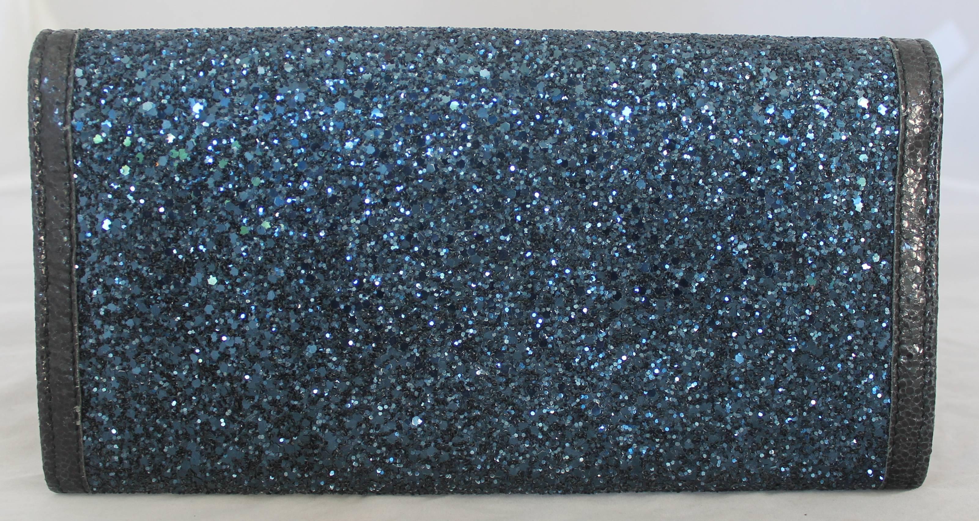 Jimmy Choo Blue Sparkle & Black Cracked Leather Clutch - GHW.  This beautiful clutch is in excellent condition.  It features a snap for its closure, gorgeous blue sparkle detail, and a smooth black leather trim.

Measurements:
Height: