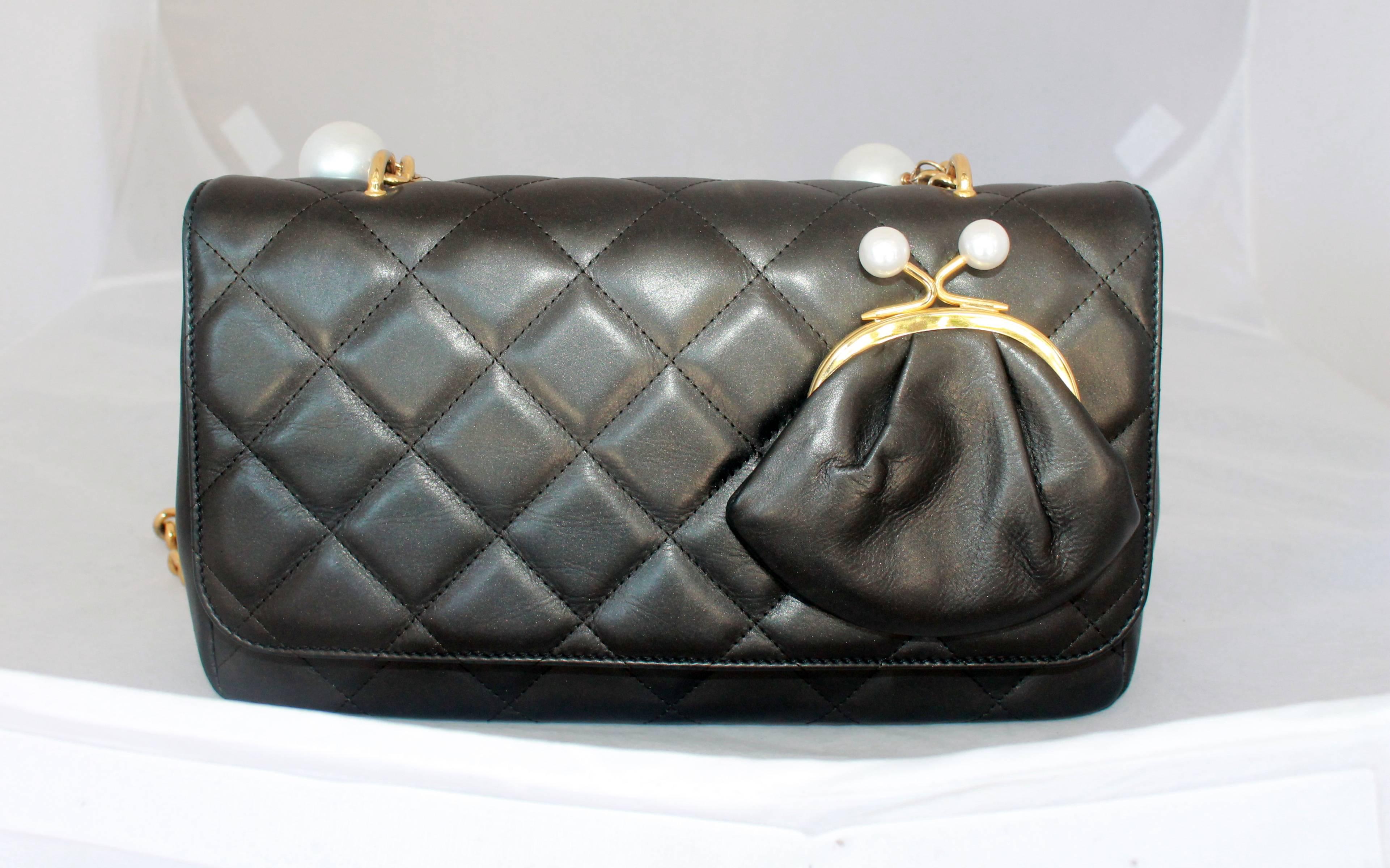 This Moschino pearlized black lambskin quilted crossbody bag is in excellent condition. It has a coin purse attached to the front that has a pearl top snap closure with a think gold link strap with over 20 hanging multi size pearls. The interior has