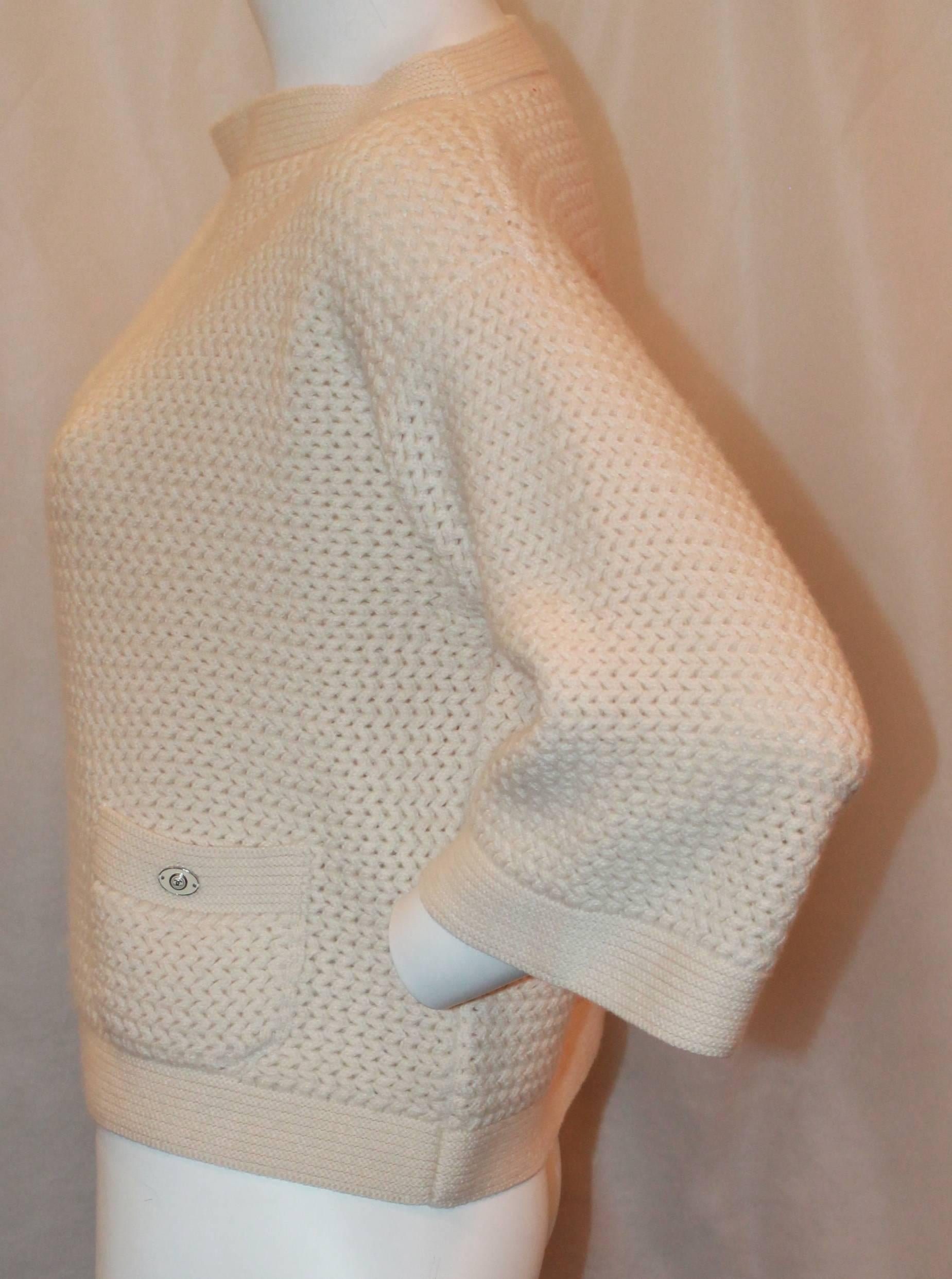 Chanel Ivory Cashmere Oversized Knitted Sweater Top - 42.  This simply beautiful sweater is in excellent condition.  It features two front pockets and an enamel Chanel logo on one of the pockets.  This sweater is absolutely gorgeous and incredibly