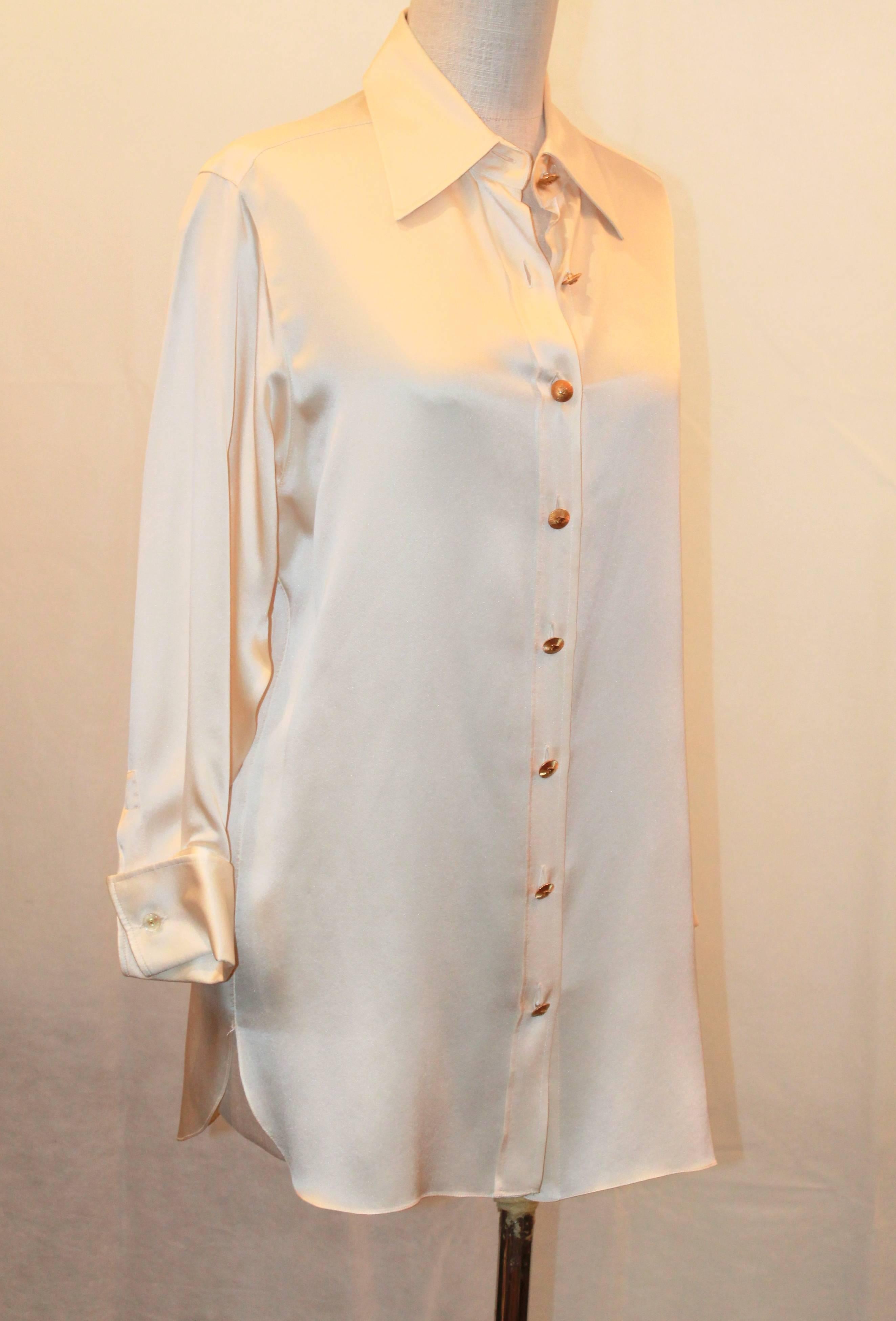 Chanel 1980's Vintage Ivory Silk Long Sleeve Blouse - M. This blouse is in very good condition and has one minor spot on the back of the collar. It is collared and has gold buttons in the front and cuff links. The cuff links are Lucite with a