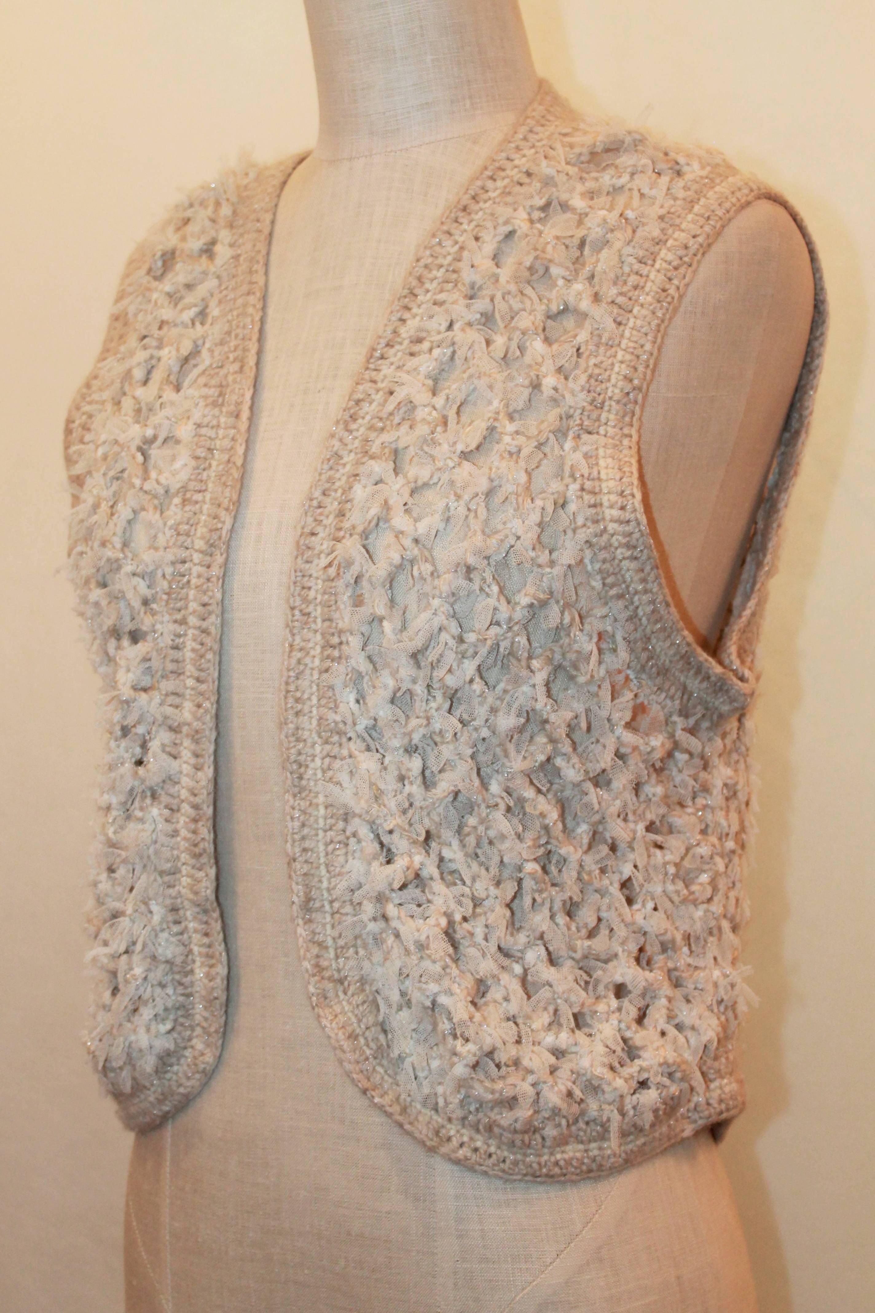Chanel Ivory & Shimmer Cashmere Crochet Vest with Beige Trim & Fringe- 40 - circa 2005. This vest is in excellent condition and has a knitted trim. The piece also has mesh threading with some shimmery threading. 

Measurements: (with vest closed,