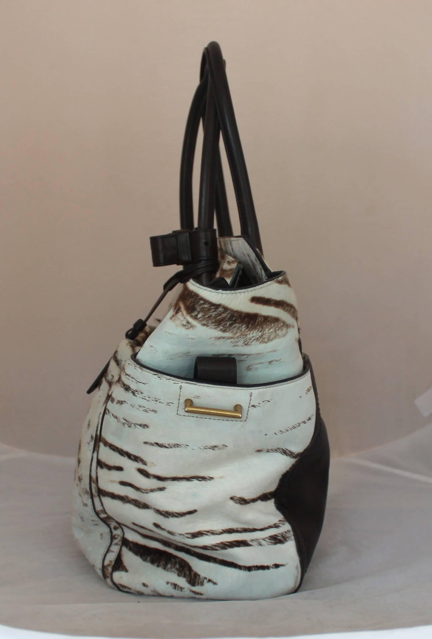 Reed Krakoff Brown and Cream Pony Hair Zebra Print Tote

This tote is pony hair with side flaps. It has a deep chocolate brown leather handle. It also has a leather section on the back, top zip, and on the side pockets of the flaps. It is in good