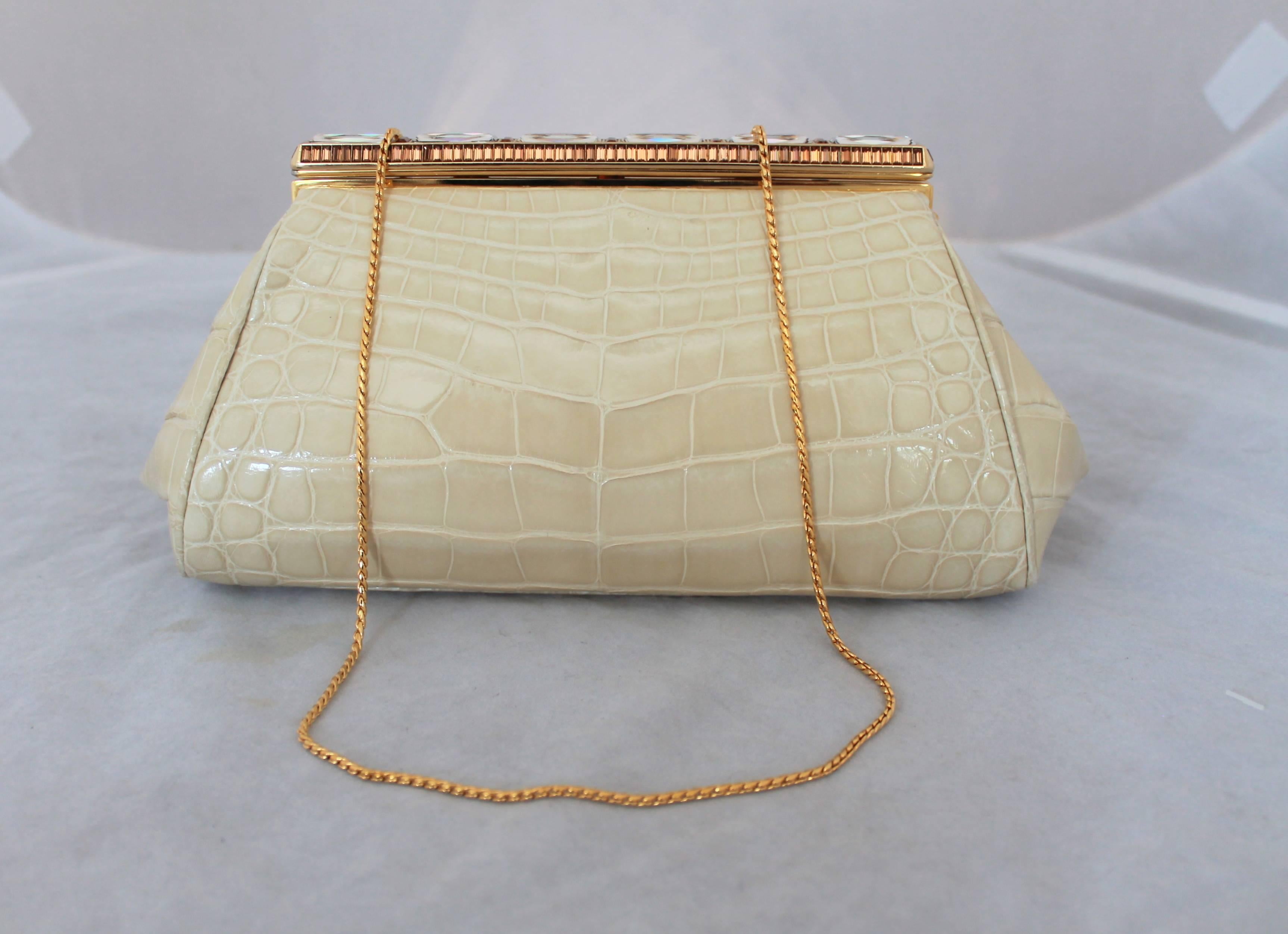 Judith Leiber Ivory Crocodile Clutch with Rhinestone and Gold Clasp. This piece is in excellent condition and has a longer gold strap. The inside lining is white leather. 

Measurements:
Height- 4.75"
Length- 8.5"
Depth-