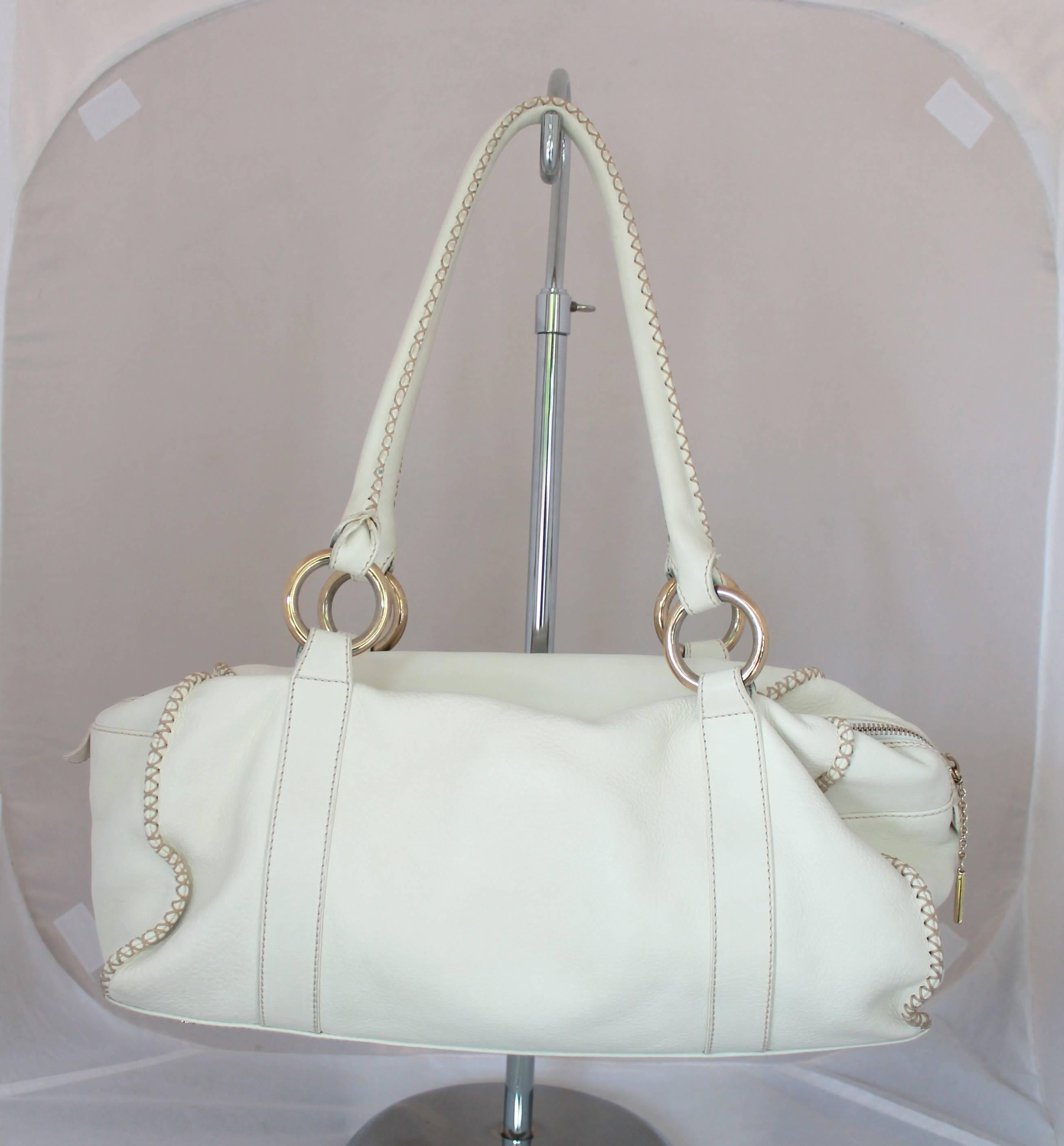 Emanuel Ungaro Ivory Leather Shoulder Bag

This ivory leather shoulder bag has beige stitched trim with front center pockets and a center zip. It has gold hardware and is in very good condition with minor staining on the handle. 
