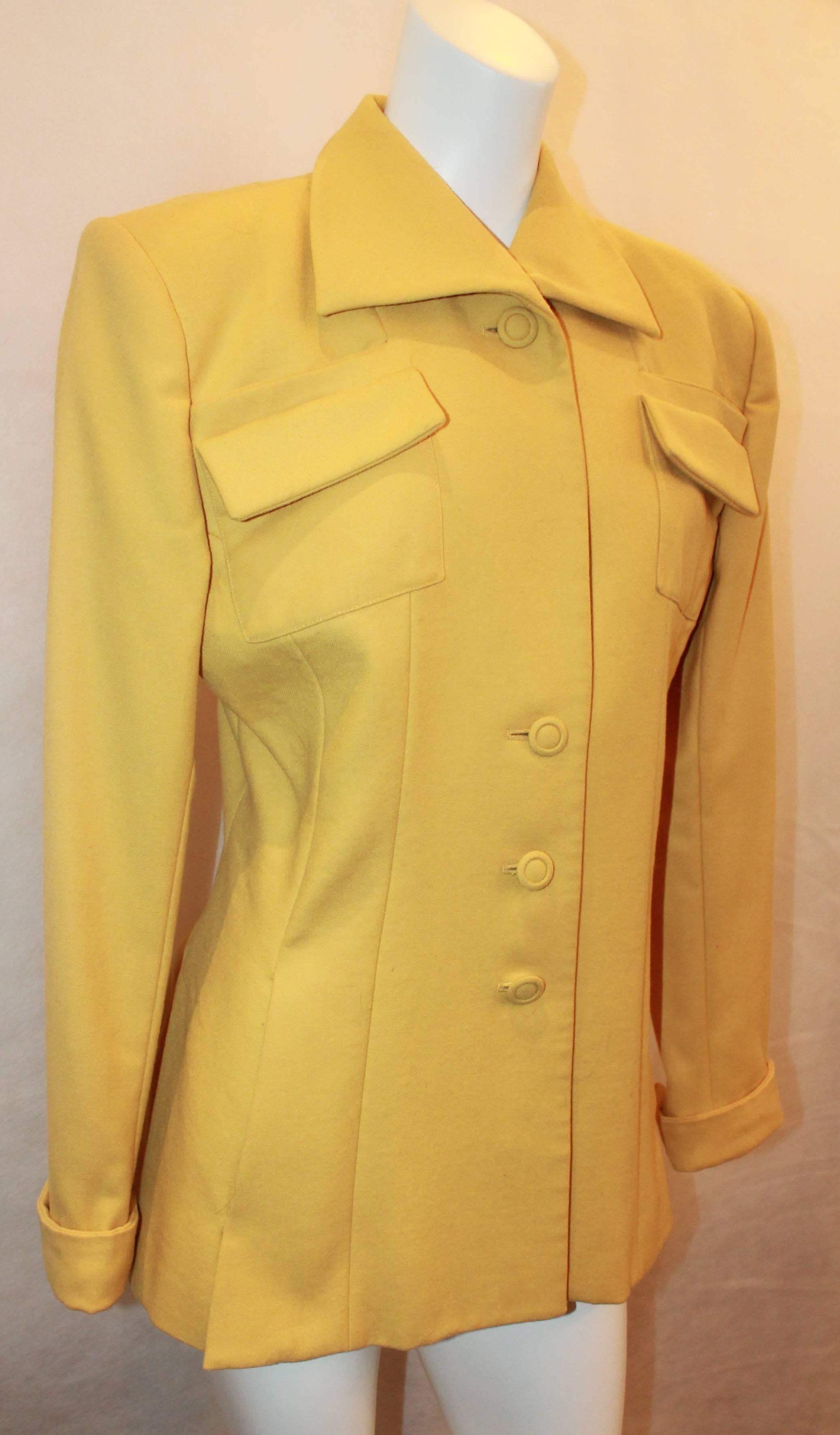 Norma Kamali 1980's Vintage Mustard Wool Jacket - 10. This jacket is in good vintage condition with some general wear all over. The jacket has 2 front pockets towards the top and 3 circular buttons. It also has shoulder pads.