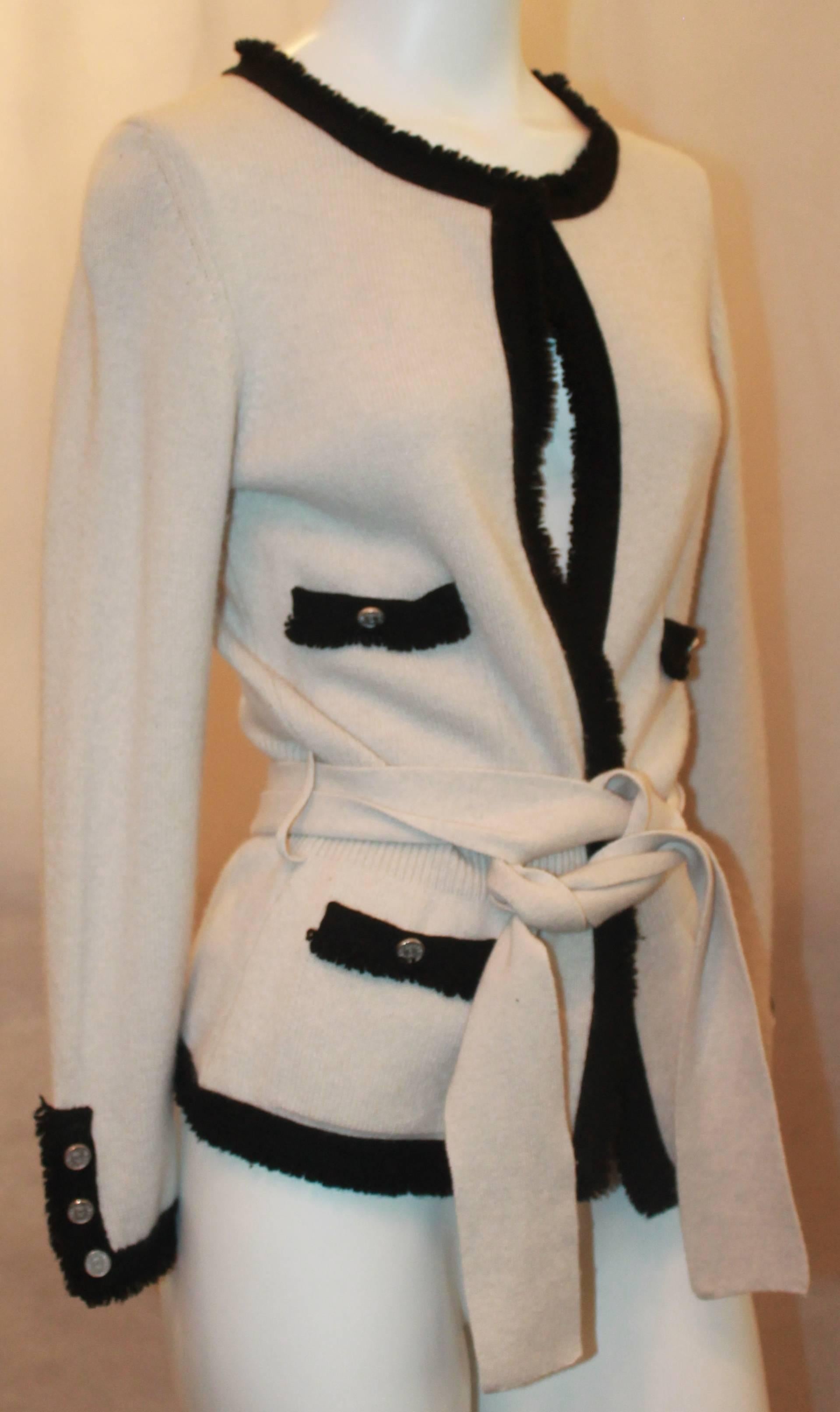 Chanel Cream Cashmere Sweater w/ Black Fringe Trim & Belt Sash - 38.  This beautiful sweater is in very good condition with only slight pilling.  It features a lovely black fringe trim, 4 front pockets, and a belt sash.  Its buttons feature the