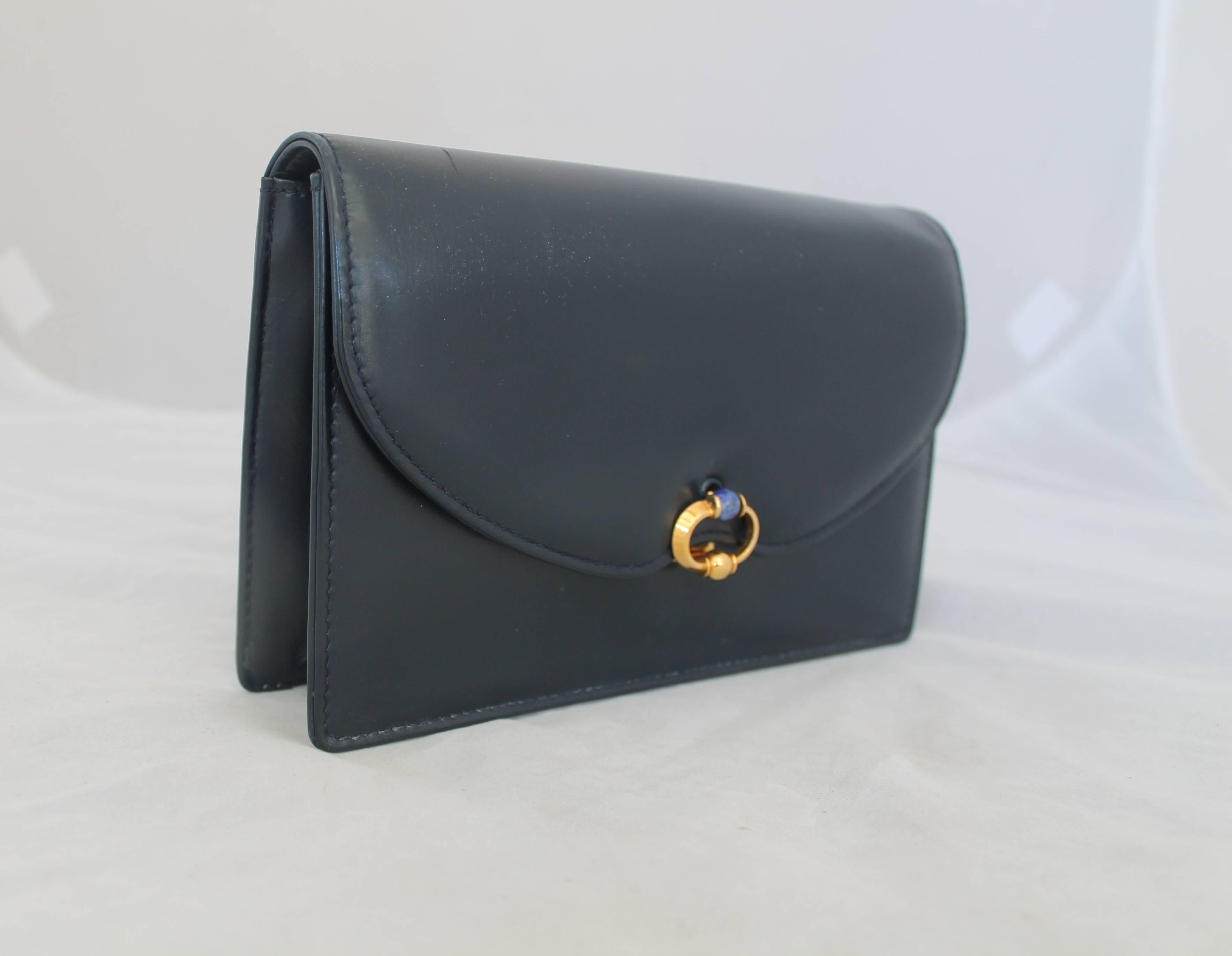 Gucci Vintage Navy Leather Clutch - GHW - Circa 1950's.  The beautiful vintage clutch is in excellent vintage condition.  It features a gold circular clasp and a blue jewel at center, a chic navy leather, a zipped compartment on the inside, and it