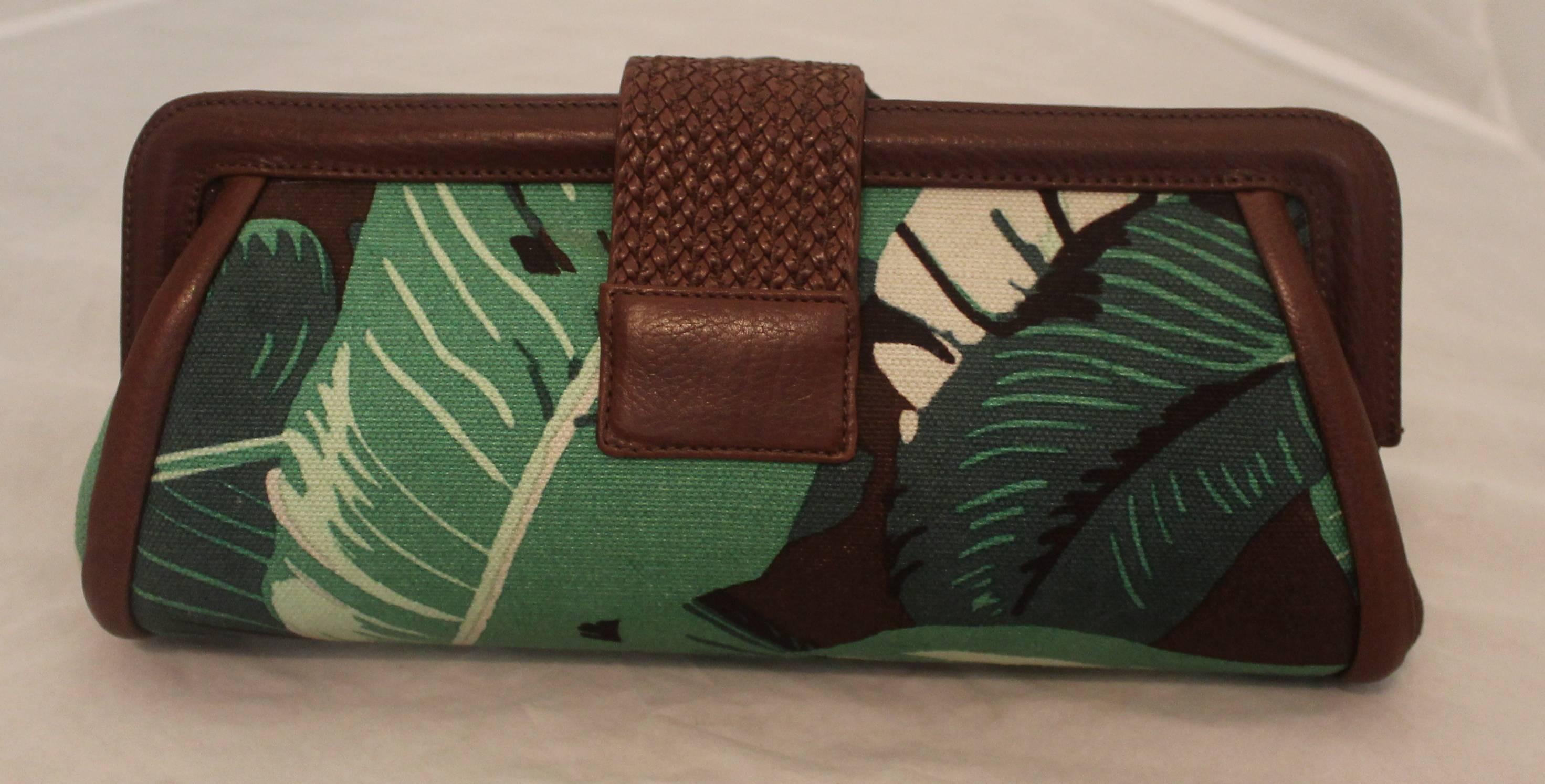 Michael Kors Green & Brown Tropical Print Clutch. This piece is in excellent condition and is perfect for the summer! There is a braided front lock with leather trim. The clutch has a gold interior and top zip.

Measurements:
Height- 5