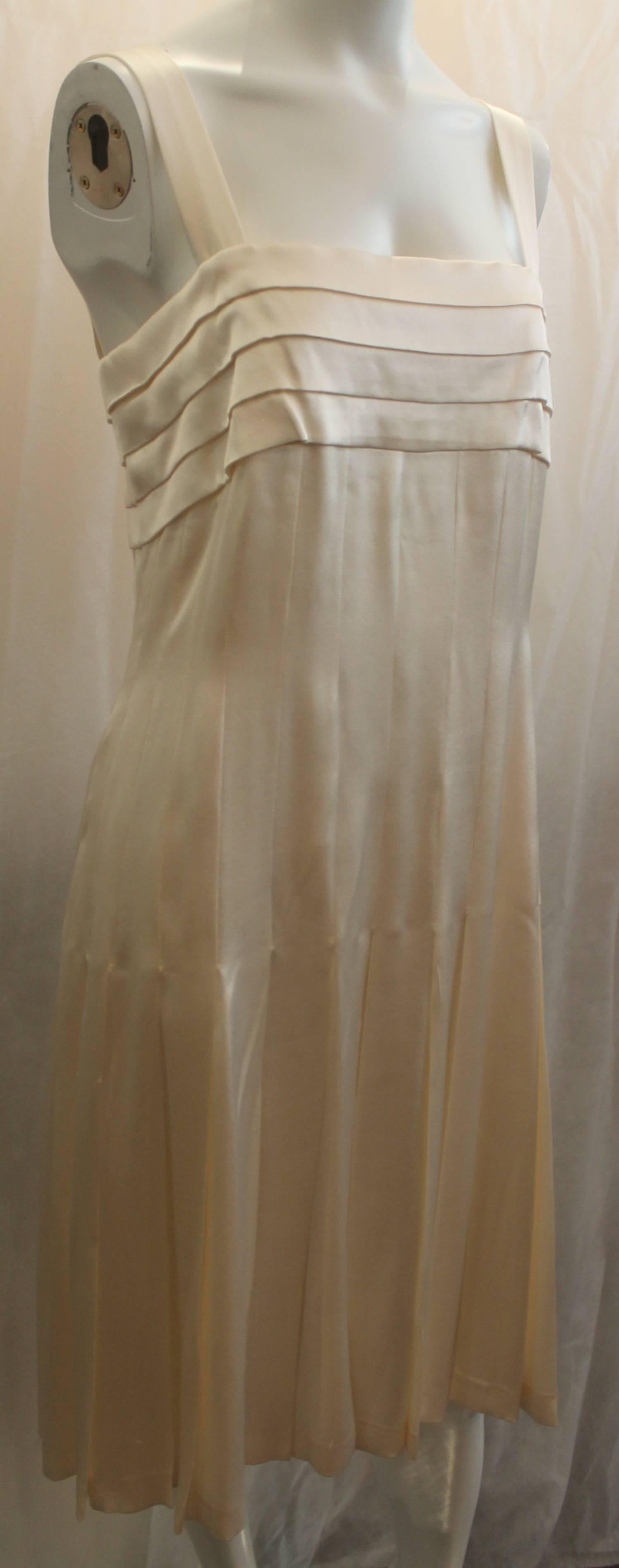 Chanel Ivory Silk Pleated Flapper Inspired Dress - 40 - 05P. This dress is a beautiful piece and is in fair condition due to some pulling throughout the garment, a couple snaps missing on the back end, and a very faint spot near the front. This