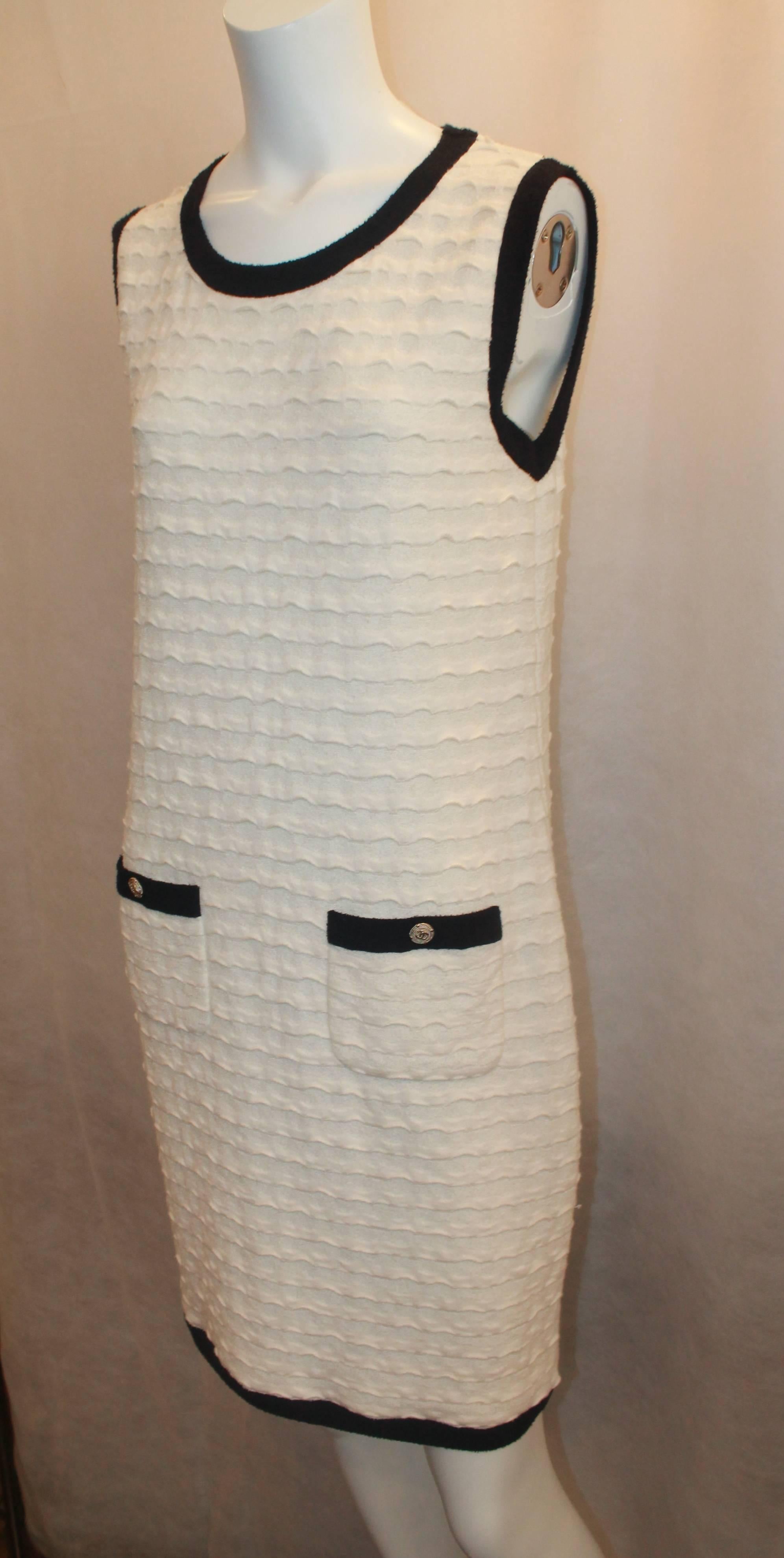 Chanel Ivory Shift Dress with Navy Trim & Pockets - 38. This dress is in excellent condition and is a classic Chanel piece. It has a ruffled look all over with 2 front pockets that have "CC" buttons. 

Measurements:
Bust-