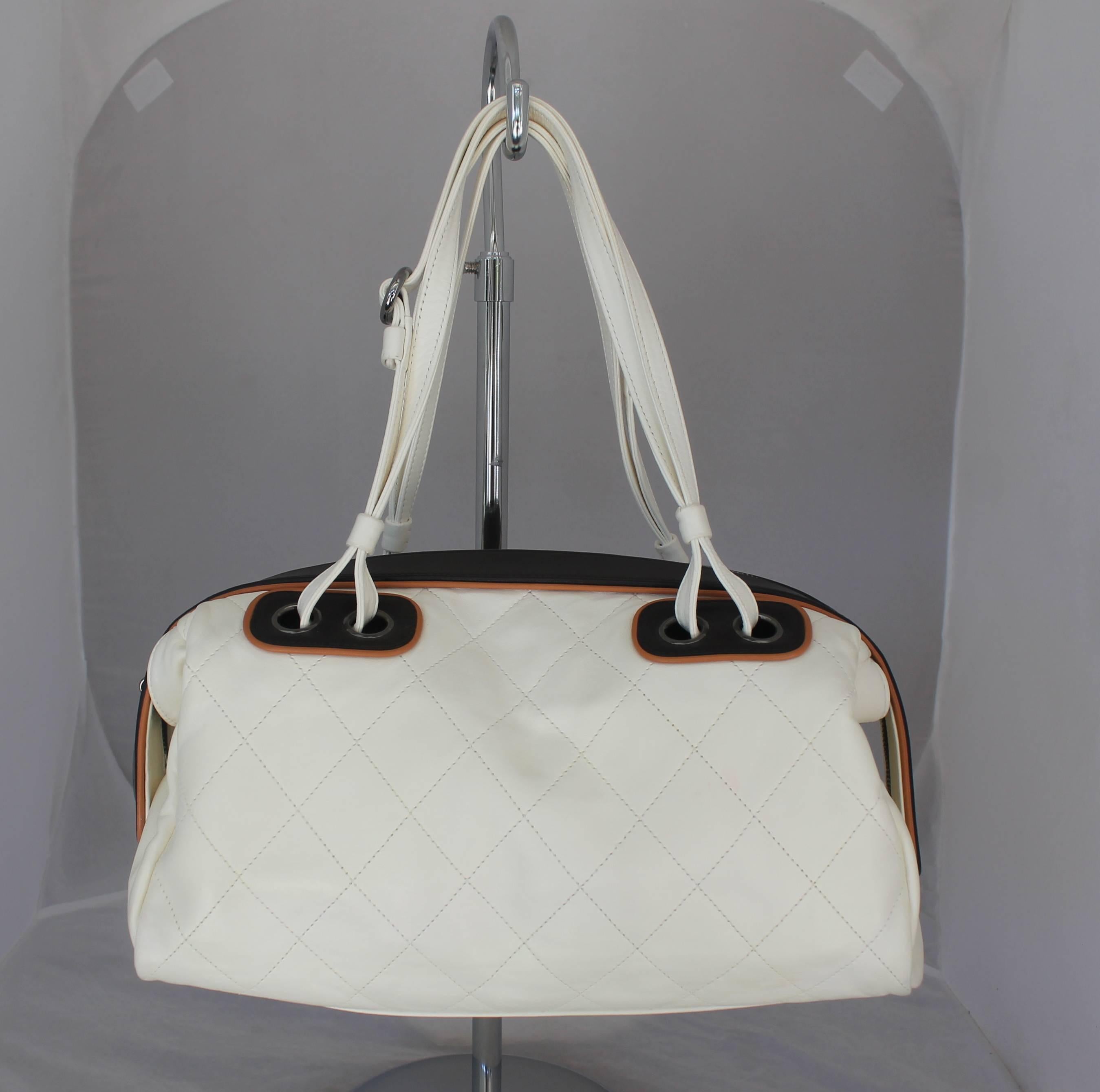 Chanel White and Black with Brown Trim Quilted Lambskin Shoulder Bag. This white shoulder bag is quilted lambskin and has a black and tan trim and palladium hardware. The flaps can come out and the black top can be tucked in. There is a 