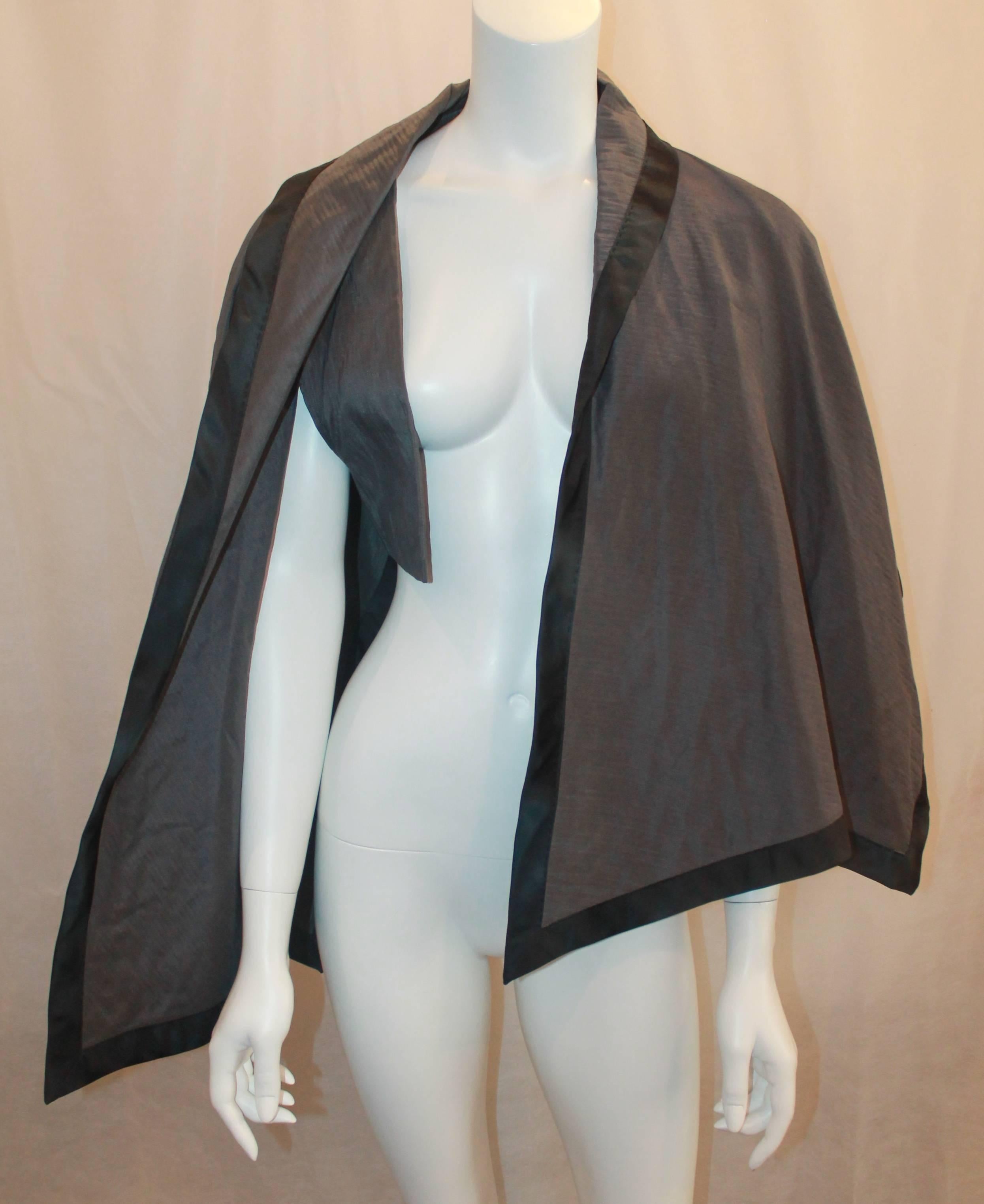 Nina Ricci Vintage Gray and Black Linen and Silk Blend Vest/Cape - Size 44. This beautiful and elegant vintage cape has an interior vest, is asymmetrical, and gray with a black trim. It is in excellent condition.

Measurements:
Bust: about