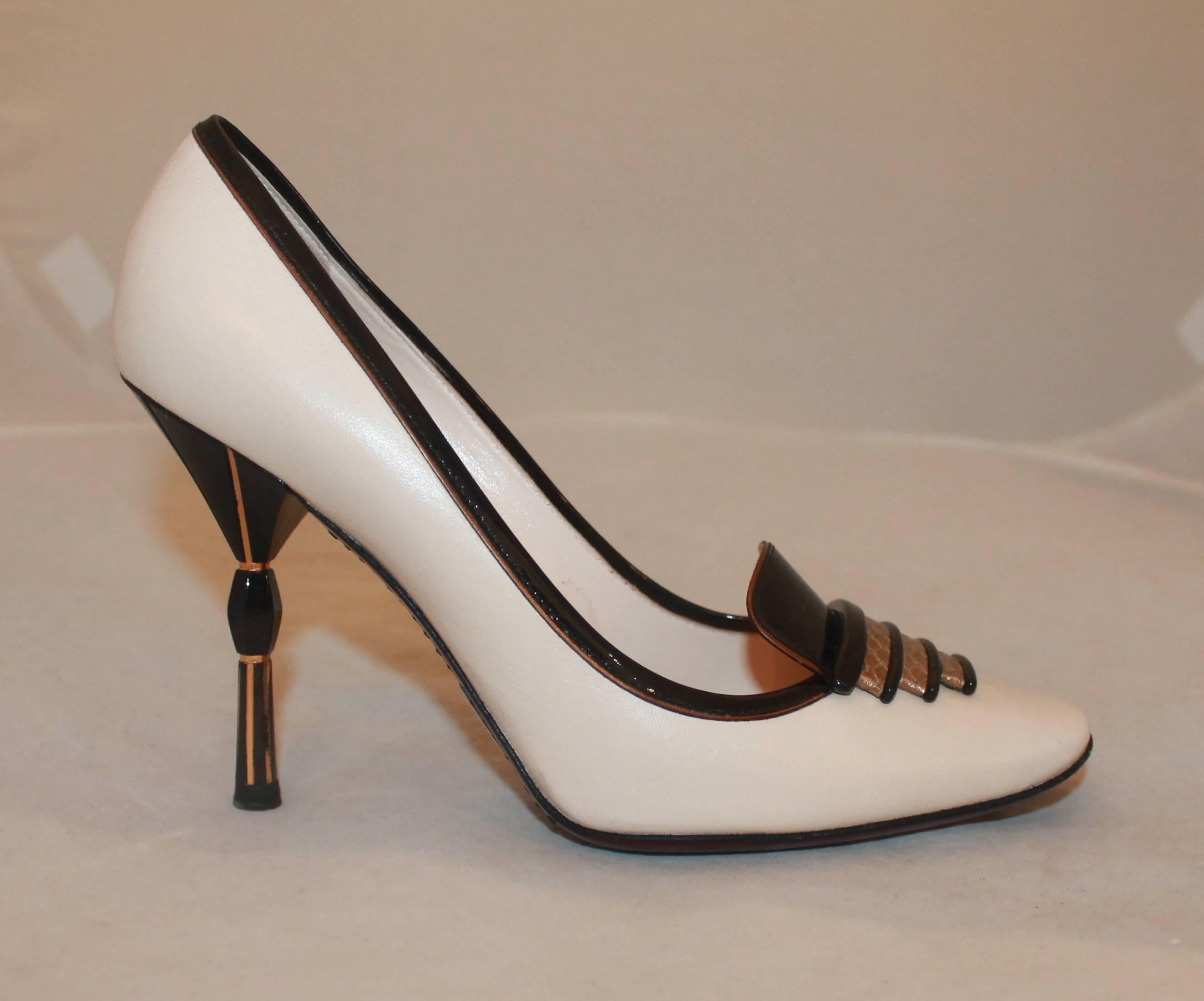 Louis Vuitton Limited Edition Art Deco Black, Ivory, and Gold Pumps - 38. These Louis Vuitton limed edition pumps are Art Deco style and are patent leather with a gold pendant int he front. The heel is black enamel with gold and are in excellent