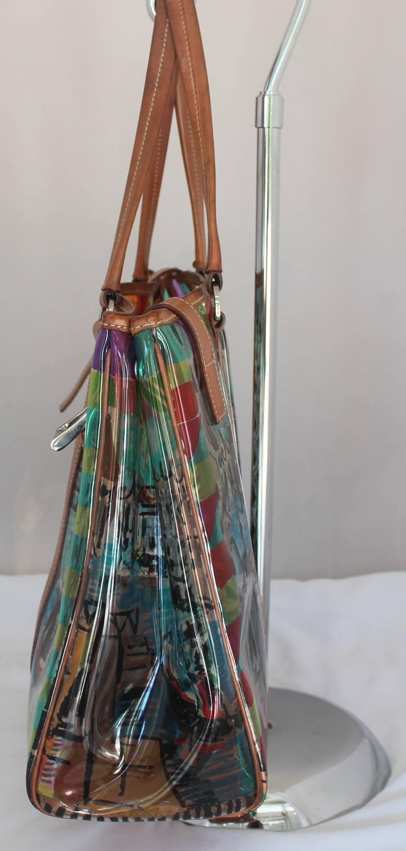 Prada Clear Multi Color Print Plastic Tote w/ leather trim/strap-SHW  HAs matching fabric makeup bag inside. 2 leather straps down front buckle, marks on leather where strap buckled. Makeup bag strap needs to be reattached to the inside of the