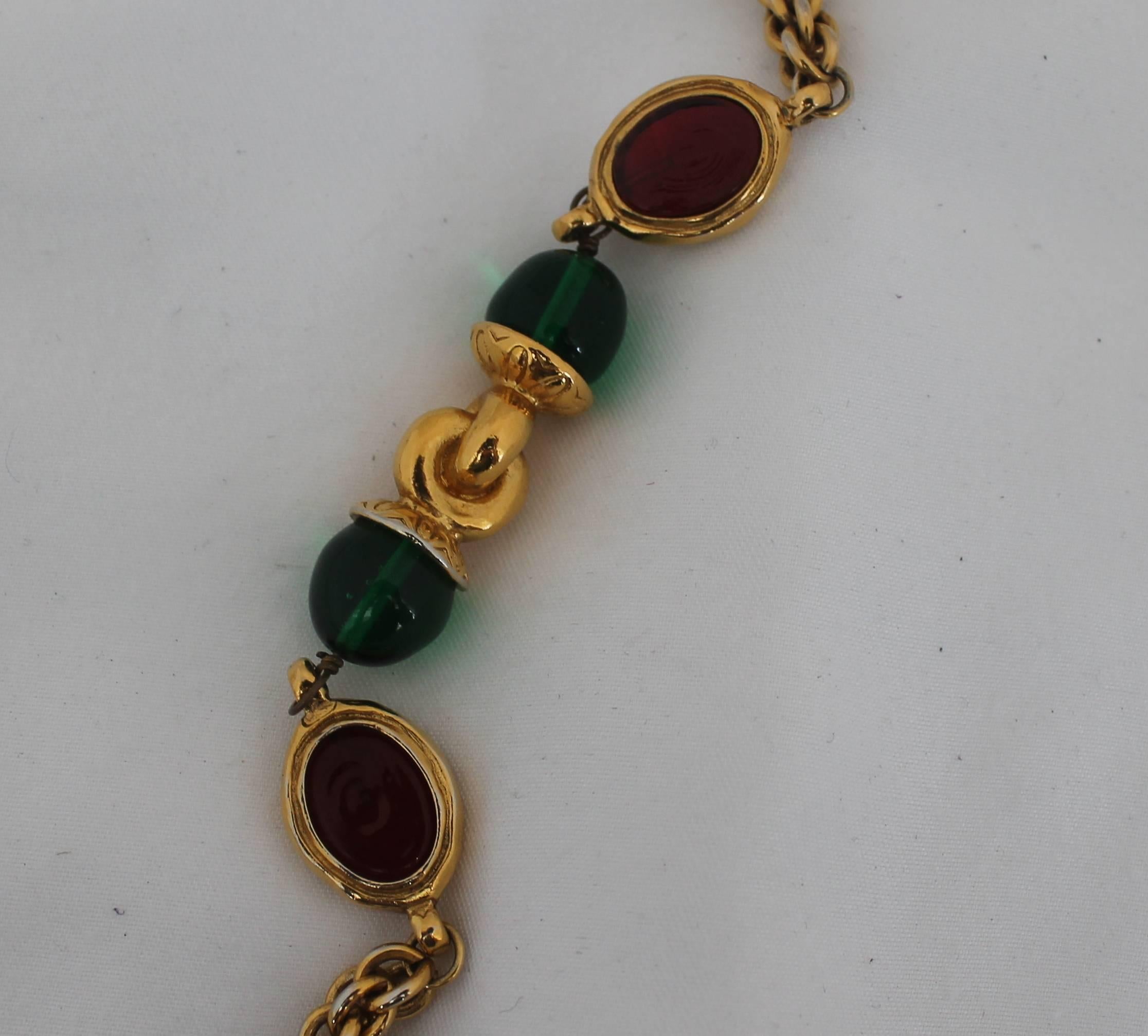 Chanel Gold and Red and Green Gripoix Necklace - circa 1970s. This Chanel necklace is made of gold links which are intertwined into a cord. There are red disks that are outlined in gold and green spheres with gold in between them. It is in good