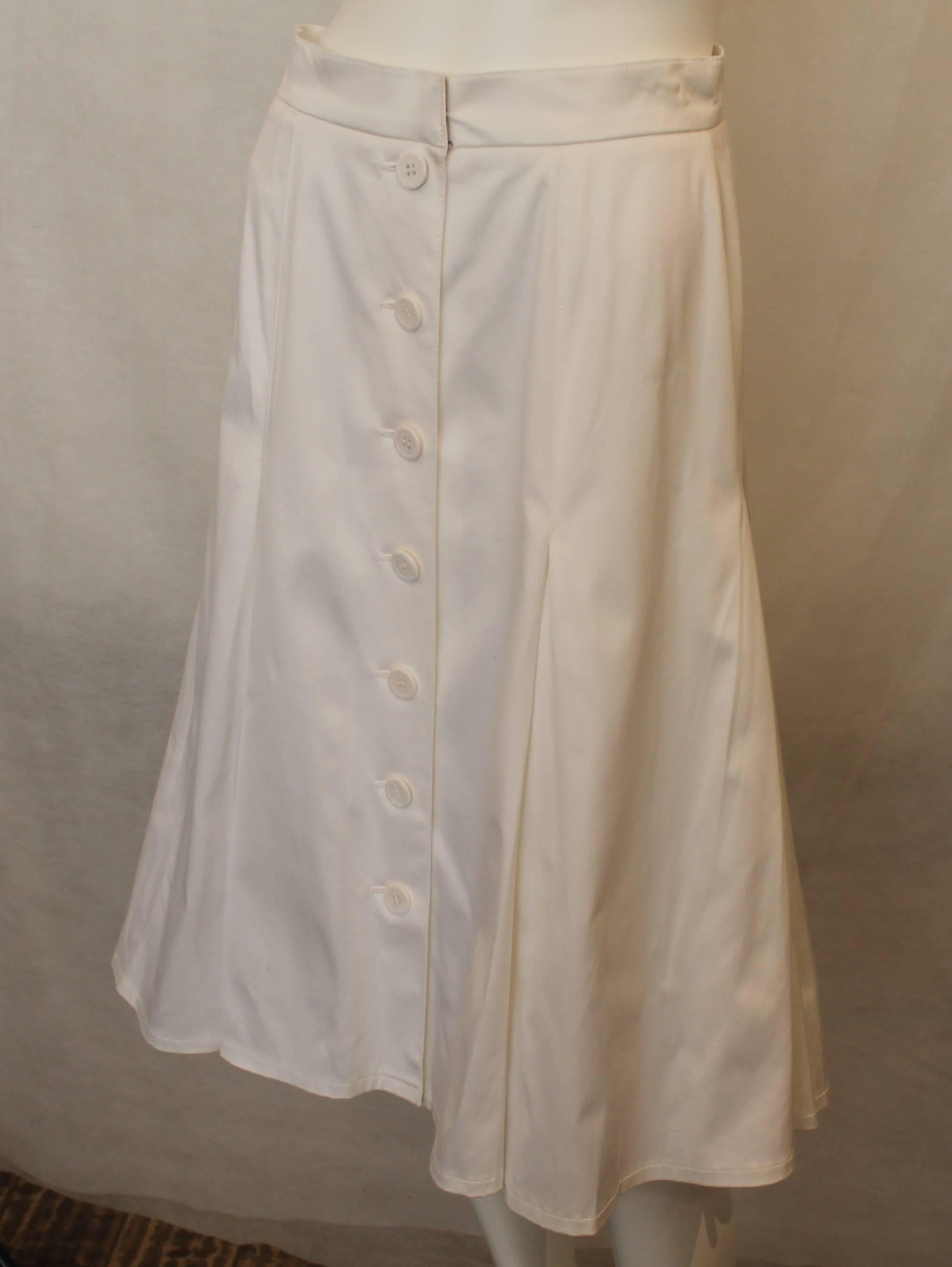 Oscar de la Renta White Cotton Tea Length Skirt with High Pleats and Buttons - 6. This  skirt is tea length and has high pleats. Buttons go down the entire front. It is in good condition with some stains near the front.

Measurements
Waist: