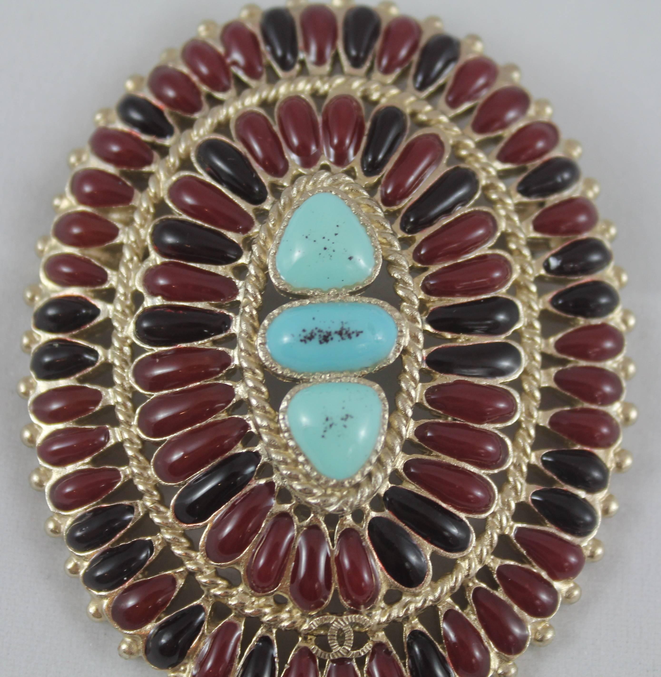 Chanel Byzantine Goldtone Red Gripoix & Turquoise Brooch - 2014. This amazing piece is in excellent condition and is from Autumn 2014. The brooch features multi-tone red gripoix stones in a circle, 3 center turquoise colored stones, entwined gold,