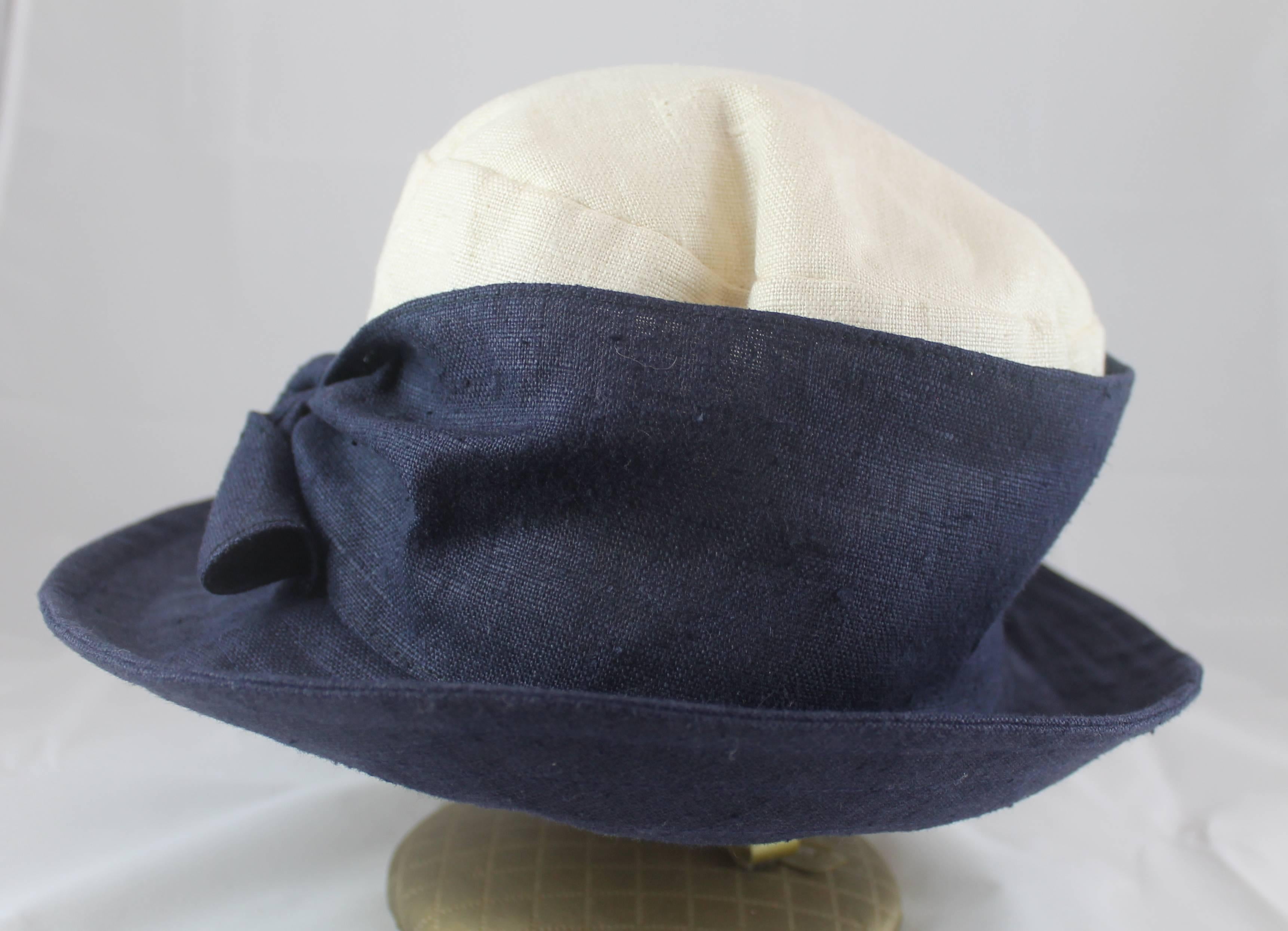 Deborah Rhodes Collection  Ivory & Navy Canvas Hat with Front Tie. This hat is in very good condition with minor pulling on the top and sides. The light weight hat is great for spring and summer.

Brim- 3