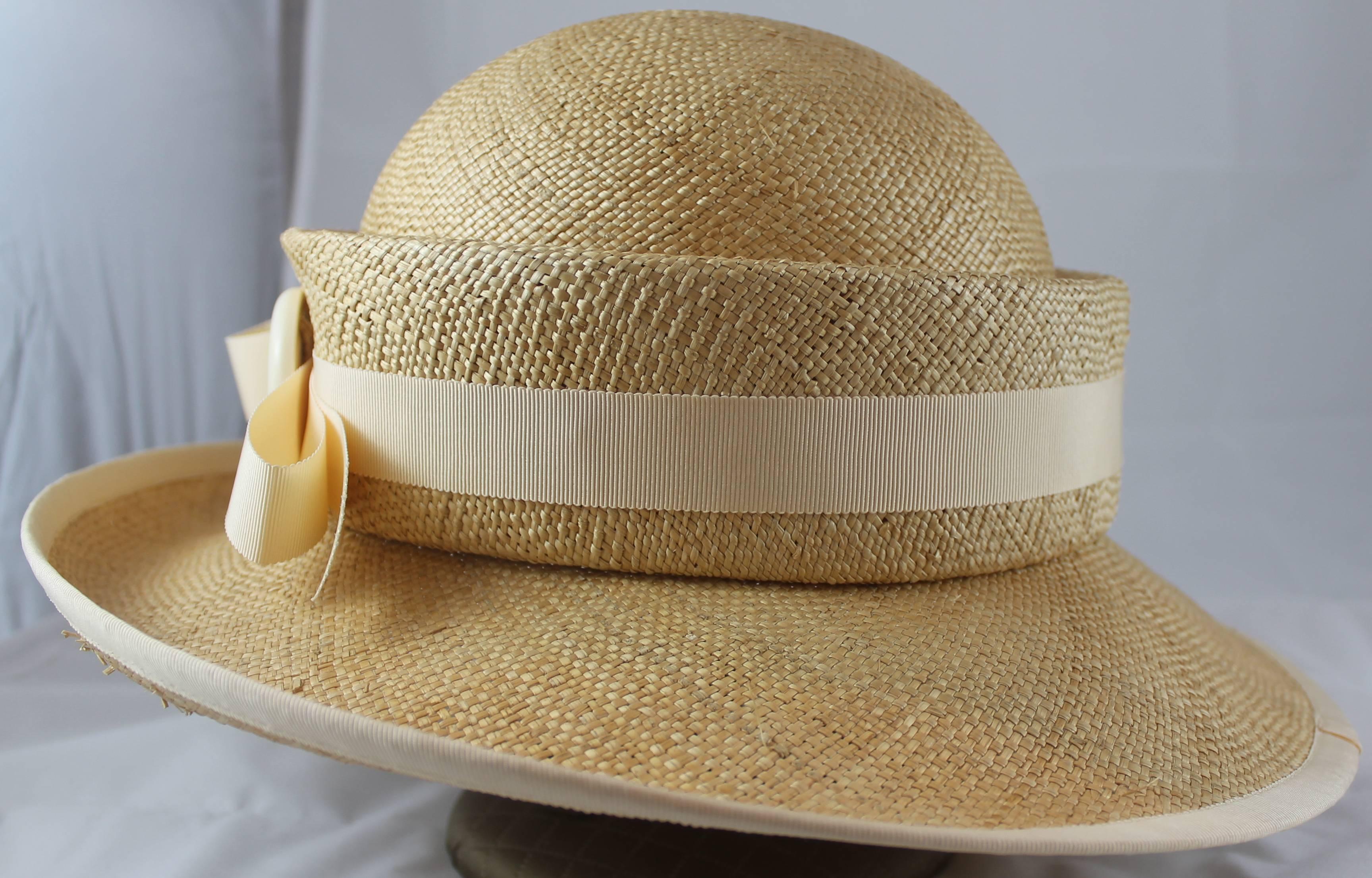 Suzanne Couture Millinery Tan Straw Hat with Ivory Ribbon Trim & Bow. This hat is in excellent condition with some sections of straw poking out on the inside. The hat features a slight front fold and extra straw trim in the center with a bow &