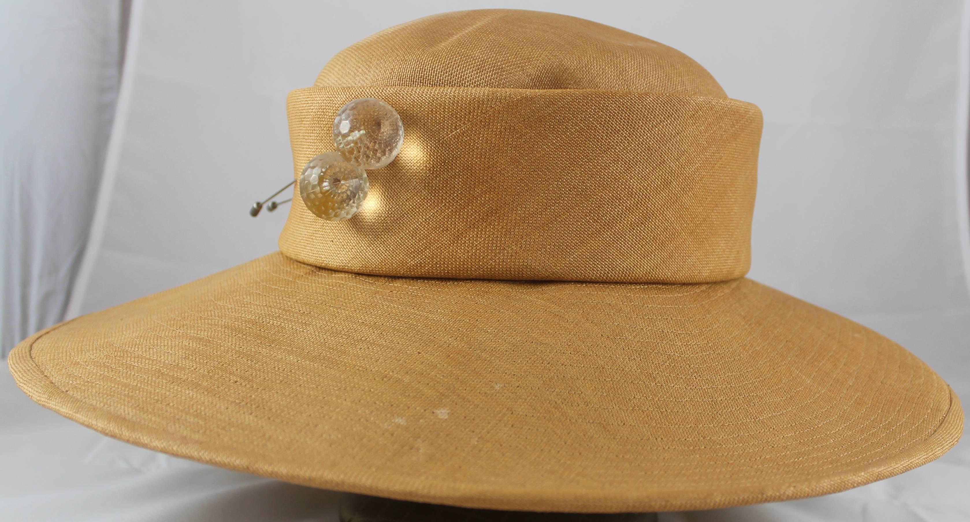 Suzanne Couture Millinery Luggage Straw Hat with Lucite Pins. This hat is in very good condition with a couple spots on the top and the brim (shown in images). The hat features a wide brim with a stitched look.

Brim- 4.25