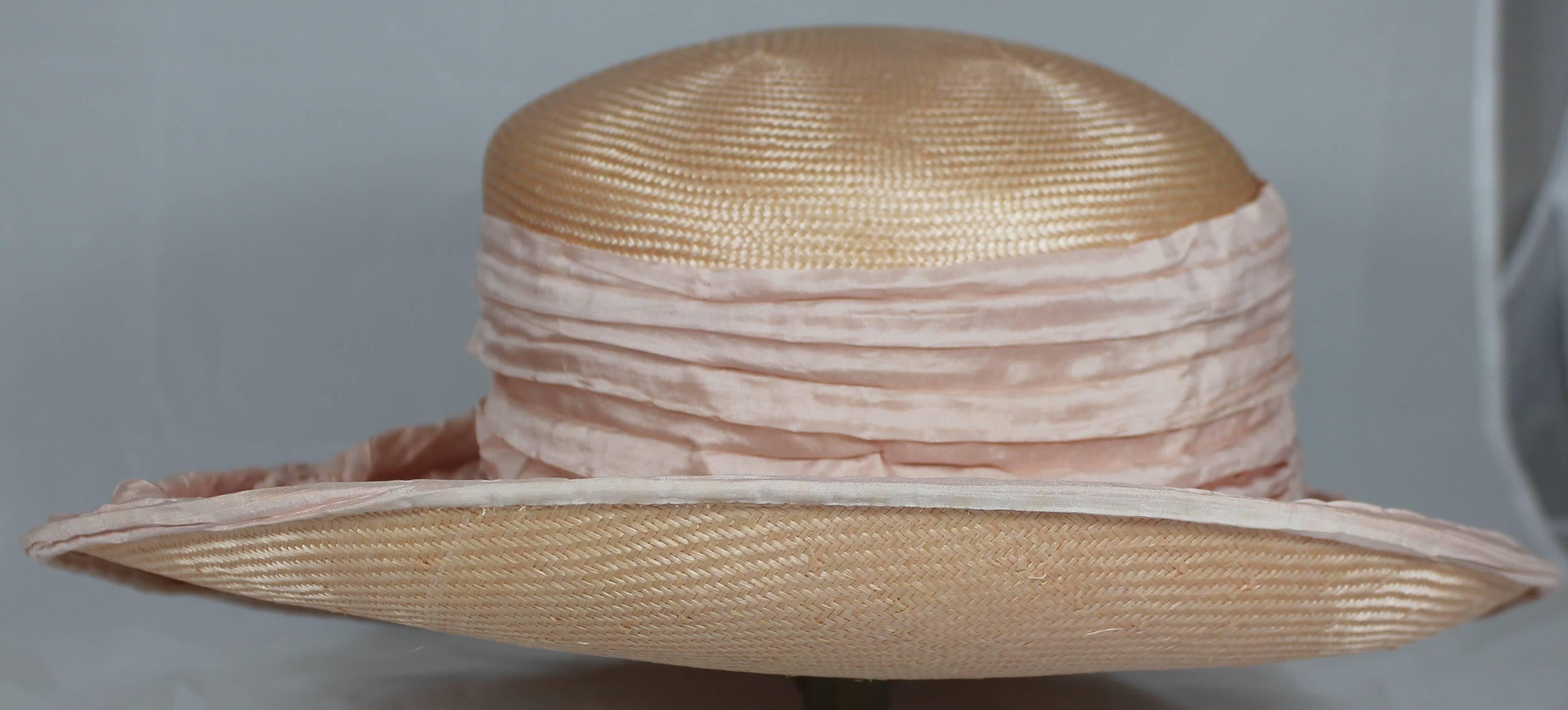 Peter Bettley London Blush Colored Asymmetrical Hat with Pink Silk Pleated Cover and 2 Flowers. This beautiful and elegant hat is of blush colored straw-like material. There is a large Silk Pleated fabric on covering the brim. There are 2 flower
