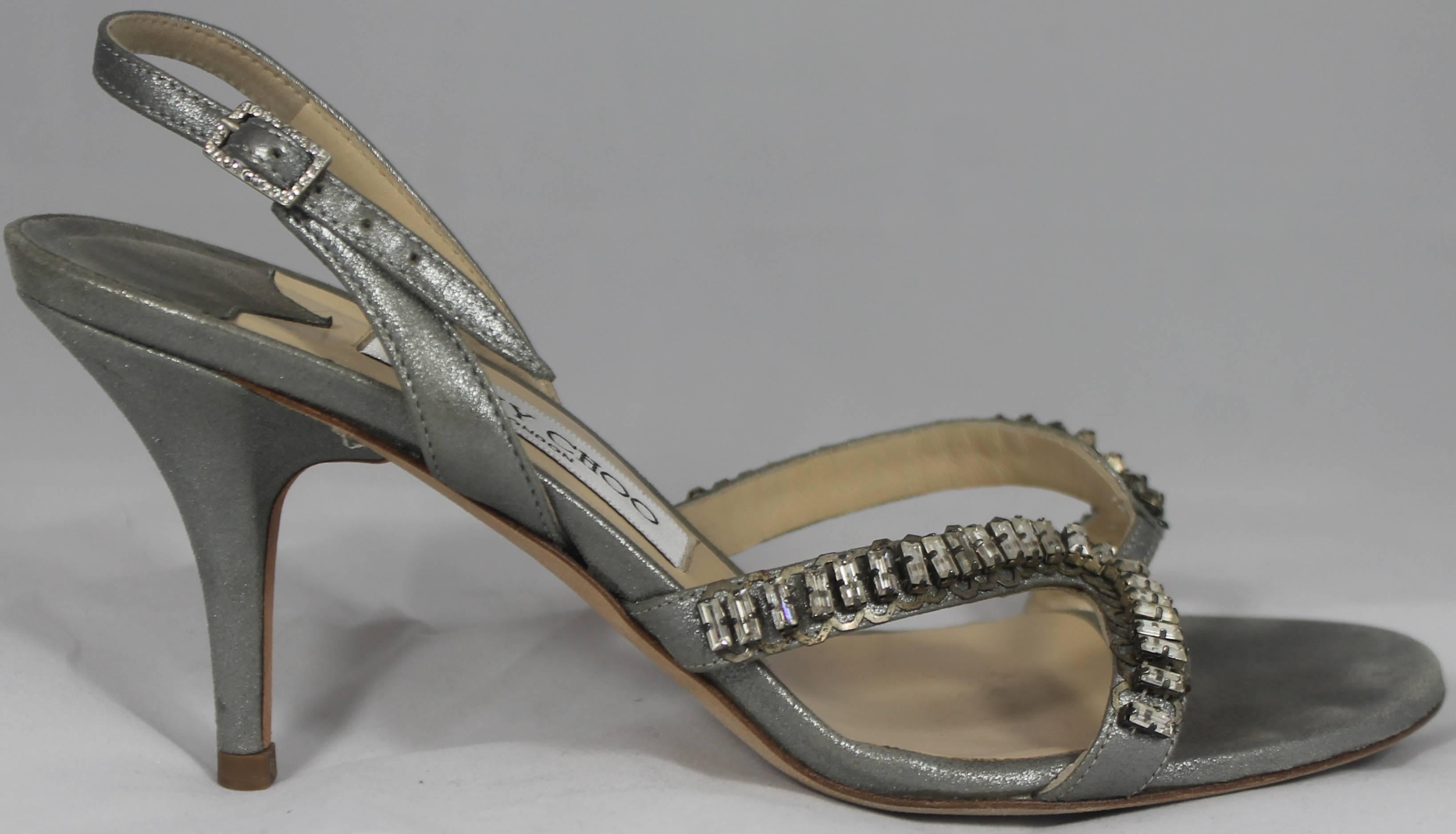 Jimmy Choo Shimmery Silver Slingback Heels with Bedazzlement - 37. These heels have a shimmery silver color. On the slingback, there is a rhinestone buckle. The front of the shoes have 2 straps that are covered in rhinestone beads. They are in good