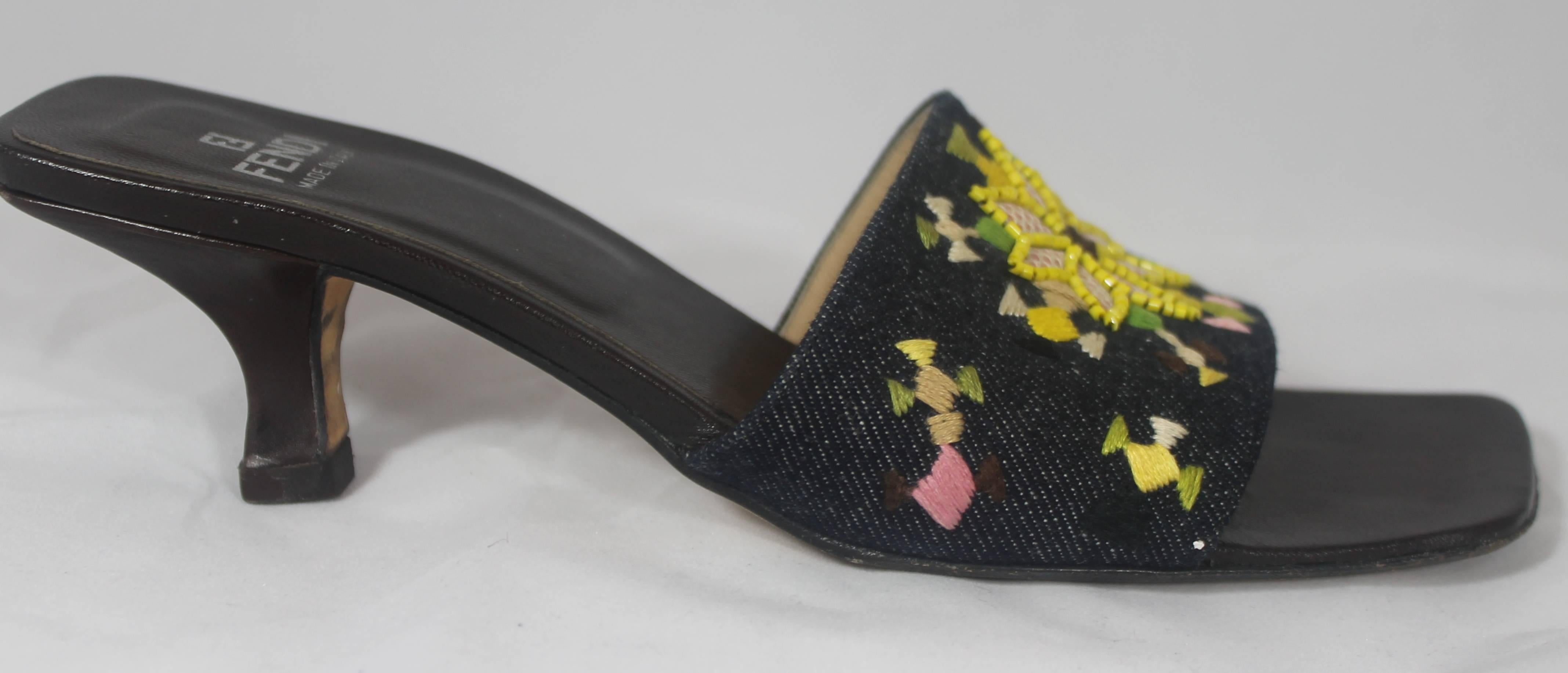 Fendi Denim Slides with Multi-Colored Embroidered and Beaded Design - 7M. These slides have a square toe shape and a band over the top of the foot. The band is denim colored and has multi-colored designs on it along with some yellow beading. They