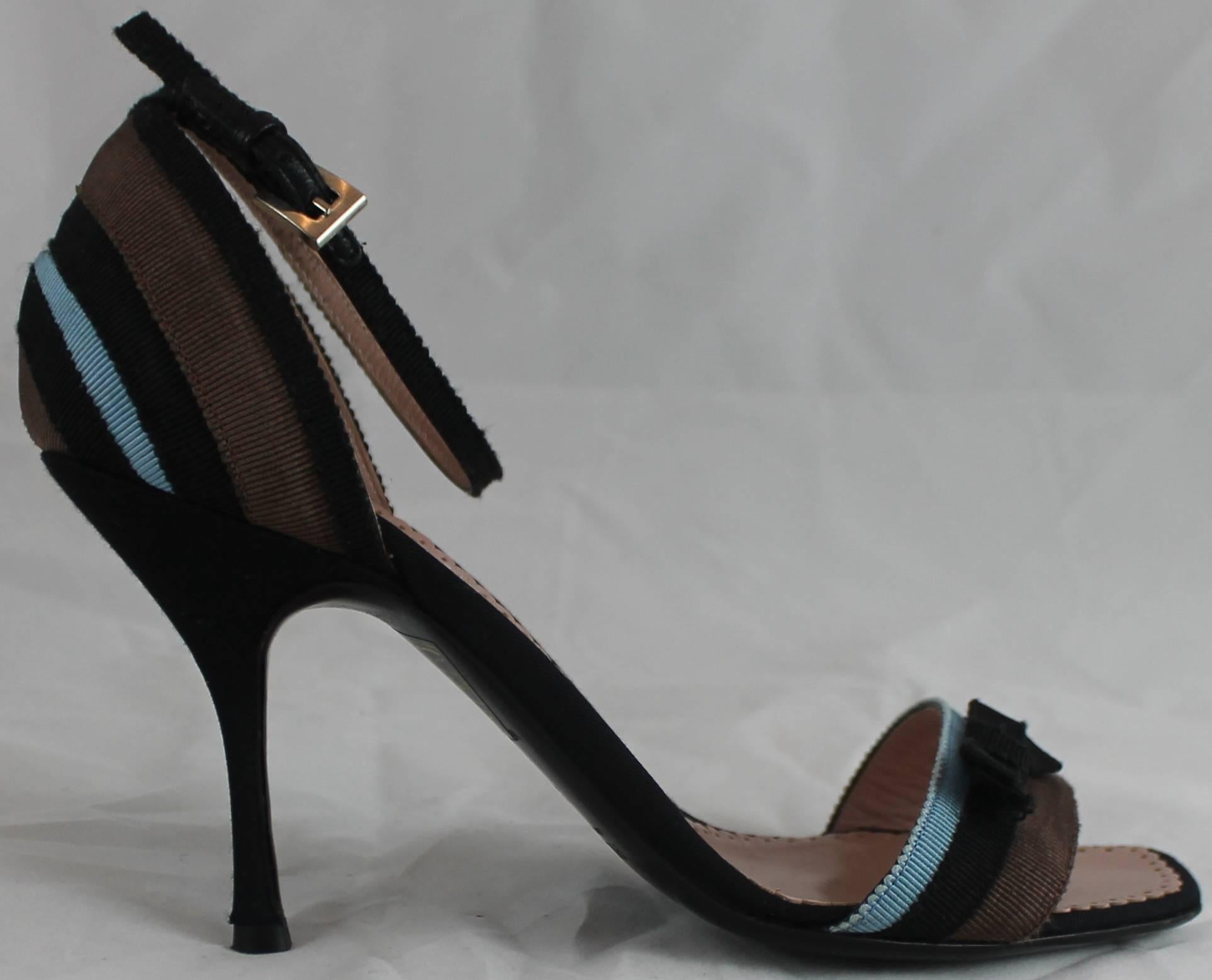 Prada Blue, Black, and Brown Grosgrain Striped Heels with Ankle Strap and Bow-36. These shoes are black with a blue, black, and brown striped grosgrain band with a small black bow. The heel is thin and these shoes come with a duster. They are in