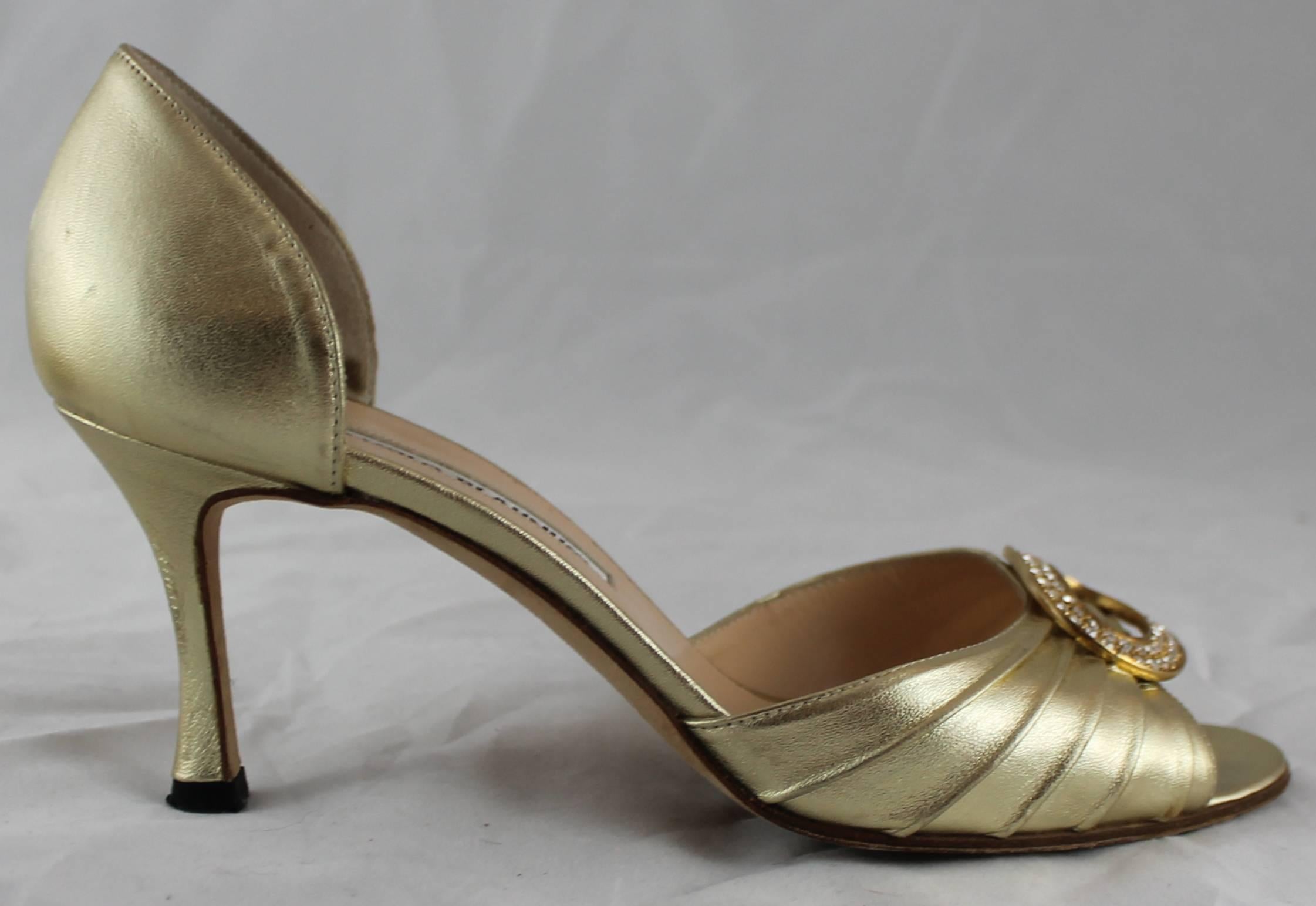 Manolo Blahnik Gold D'Orsay Heels mit Strass Detail - 36,5. Diese Fersen sind eine glänzende goldene Farbe mit einer offenen Zehe. Das vordere Band ist in Falten gelegt und mit Strasssteinen besetzt. Sie sind in sehr gutem Zustand mit geringem