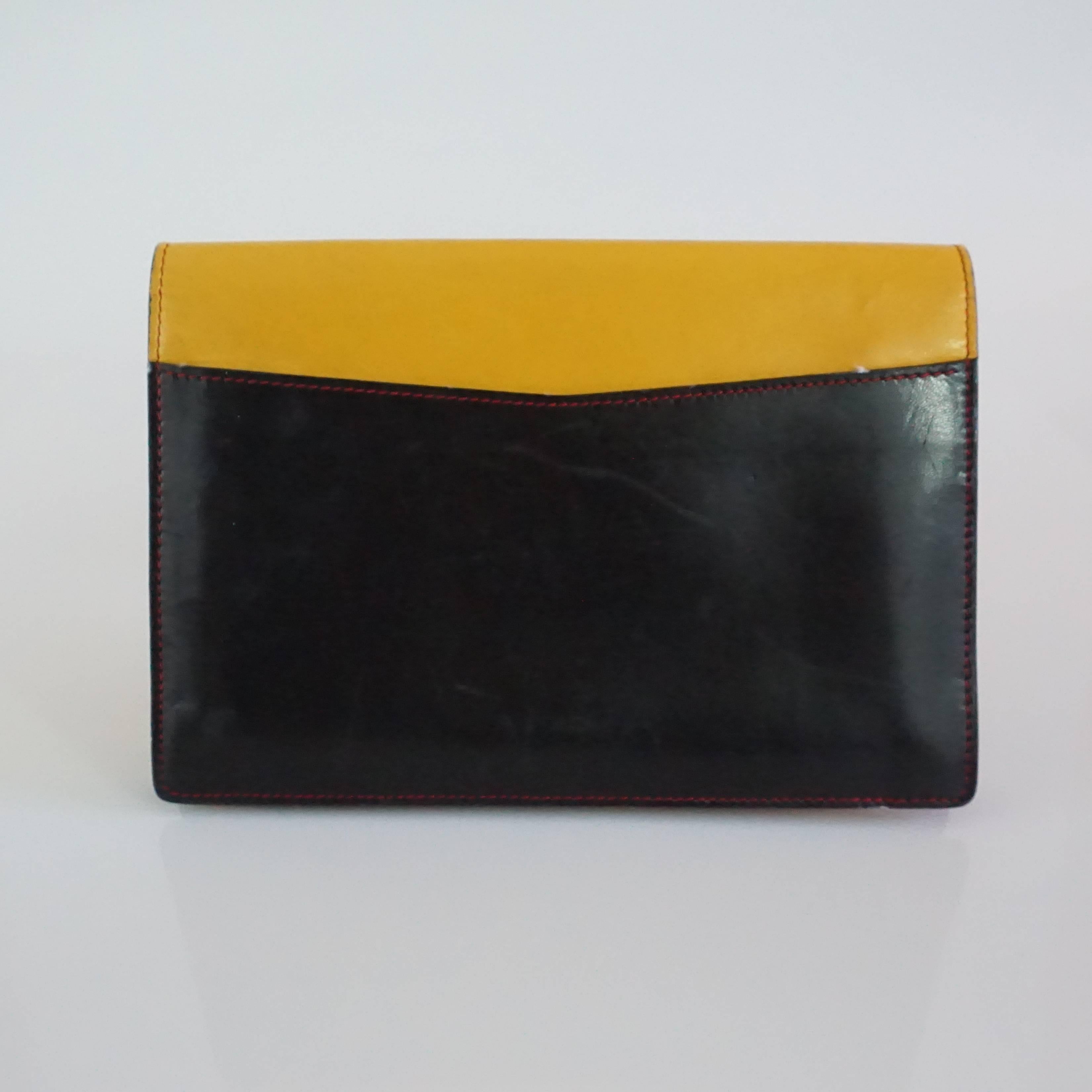 Isabel Canovas Black & Mustard Leather Envelope Clutch with Masquerade Detail - 1980's. This clutch is in fair vintage condition with visible markings on the leather such as those shown in the images; the masquerade charm and the inside lining have