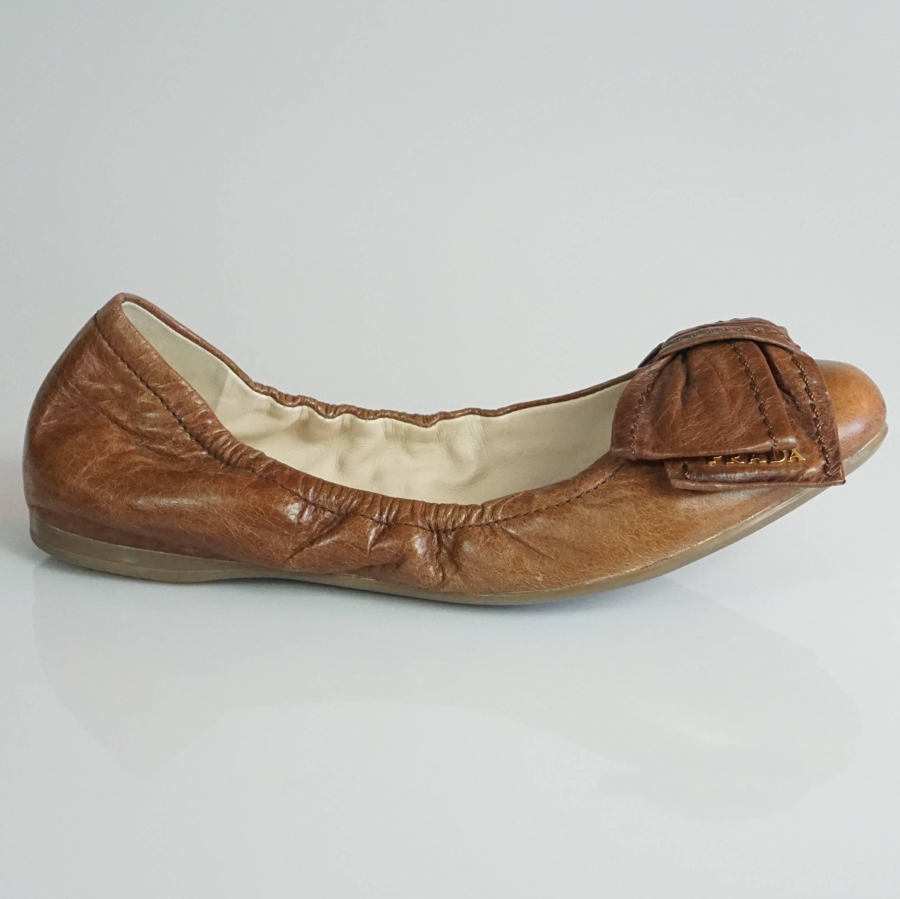 Prada Brown Leather Scrunch Ballet Flats with Bow - 35. These shoes are very versatile and a great staple piece. They feature front bows with the gold Prada logo on the ends.The flats are in good condition with some wear on the front and back of one