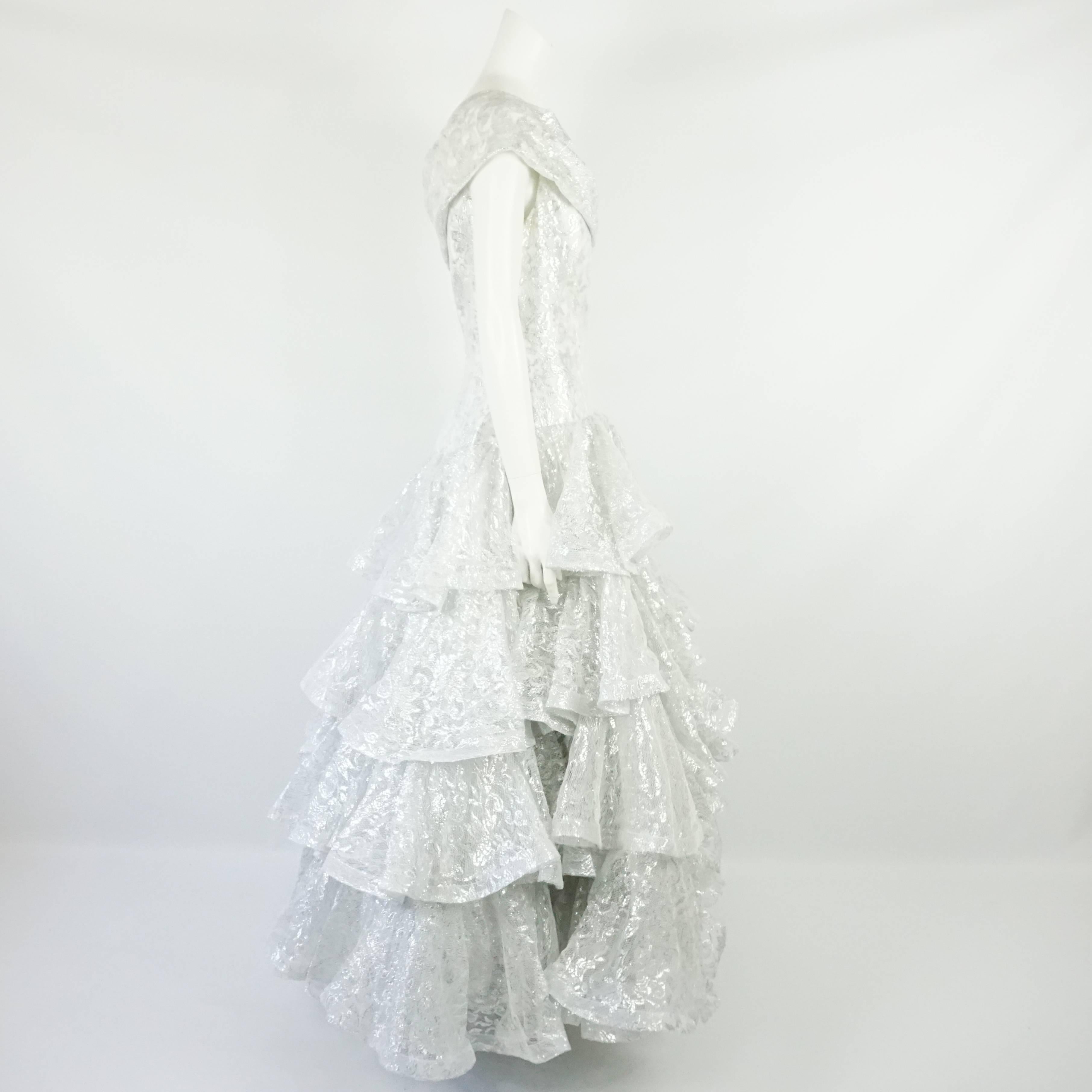 Scaasi White and Silver Silk Lace One-Shoulder Ruffled Ball Gown - 10. Circa 90's. This beautiful gown has 4 tiers of layered ruffles. There is 1 layer of lace, 2 of tulle, and 1 inside layer of white silk lining. The bodice is fitted and has a