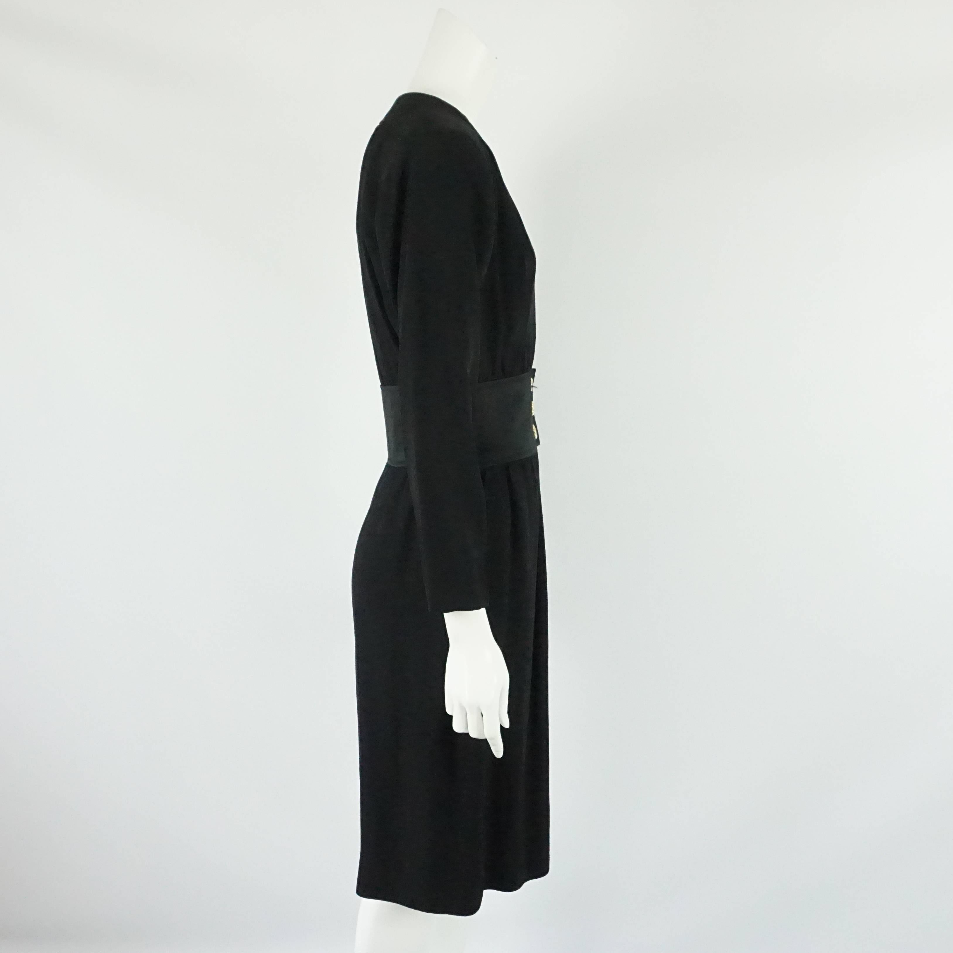 Yves Saint Laurent - Robe à manches longues en crêpe de laine noir - 40 ans - circa 70's  Cette spectaculaire robe vintage YSL a un décolleté plongeant avec quelques crochets et œillets pour la porter plus fermée si désiré, elle a une ceinture en