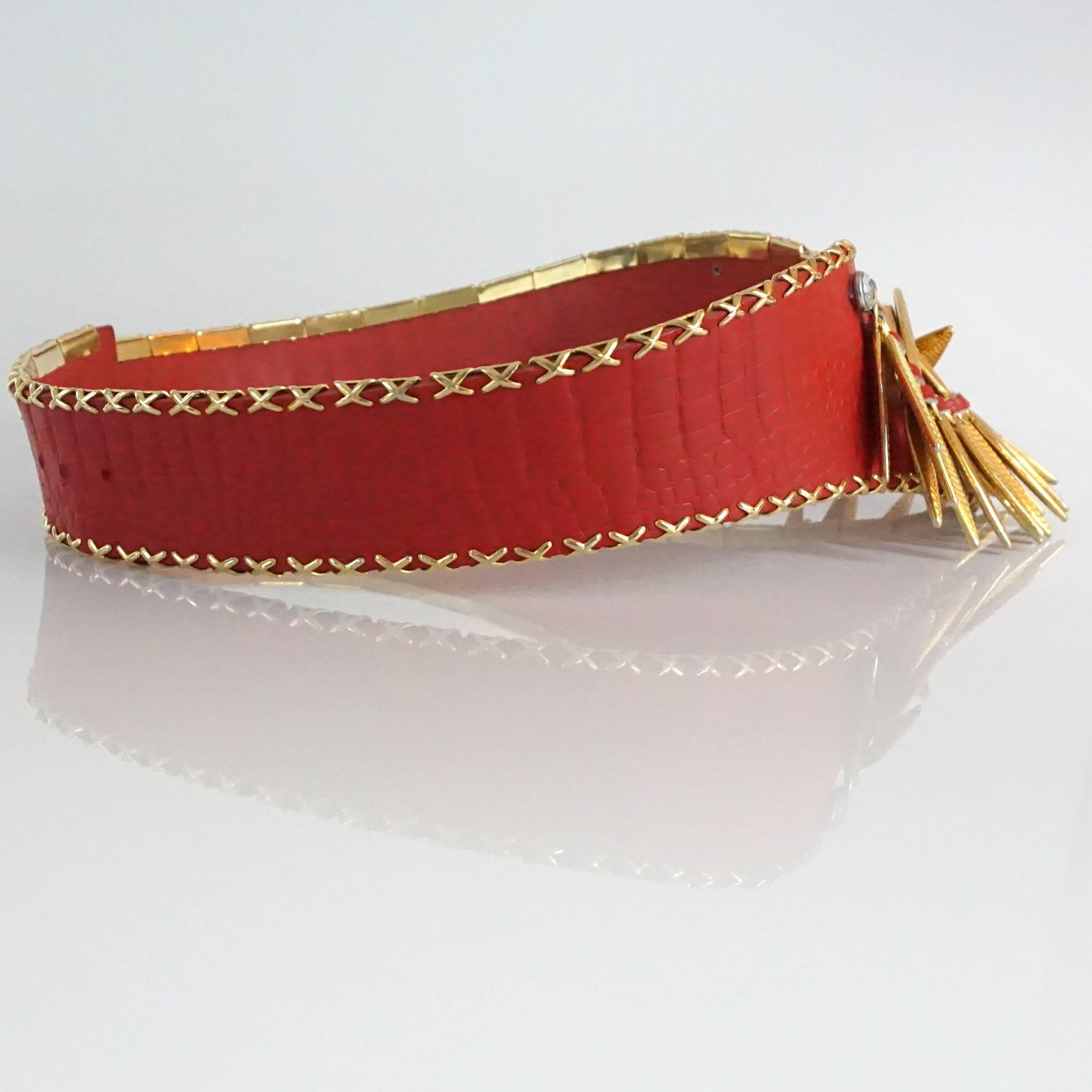 This Jose Cotel red croc embossed belt has a gold detailed metal trim with a woven leather chain in the front that has etched gold leaves. The belt is vintage from the 80's and has a v-shape. Its closure is a hook that closes in the back. It is in