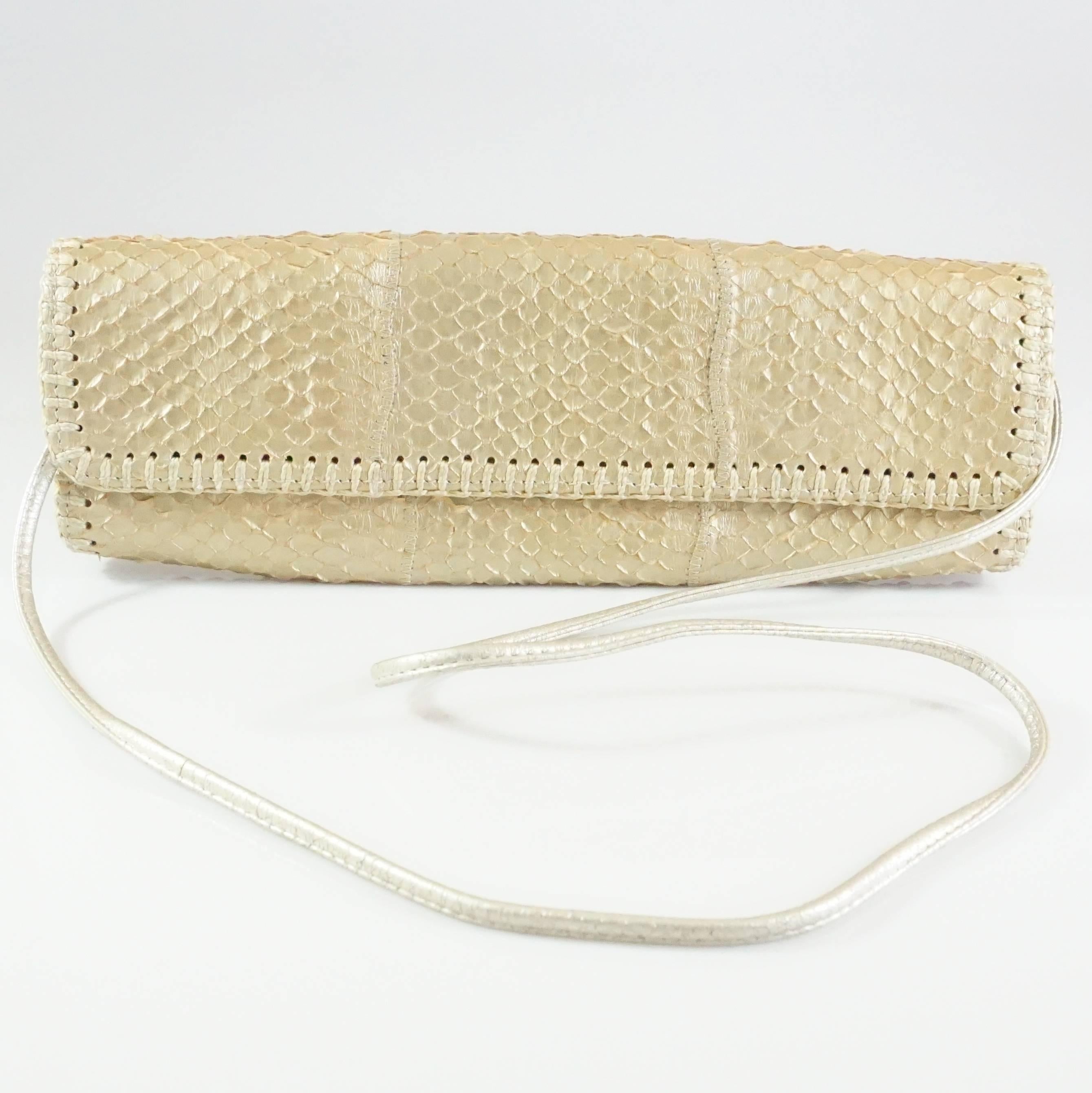 Carlos Falchi Gold Snake Clutch with Strap and Woven Detail. This gorgeous bag has a fold over style with a printed satin & leather lining. It comes with a longer strap and features a woven trim all around. It is in excellent condition with slight