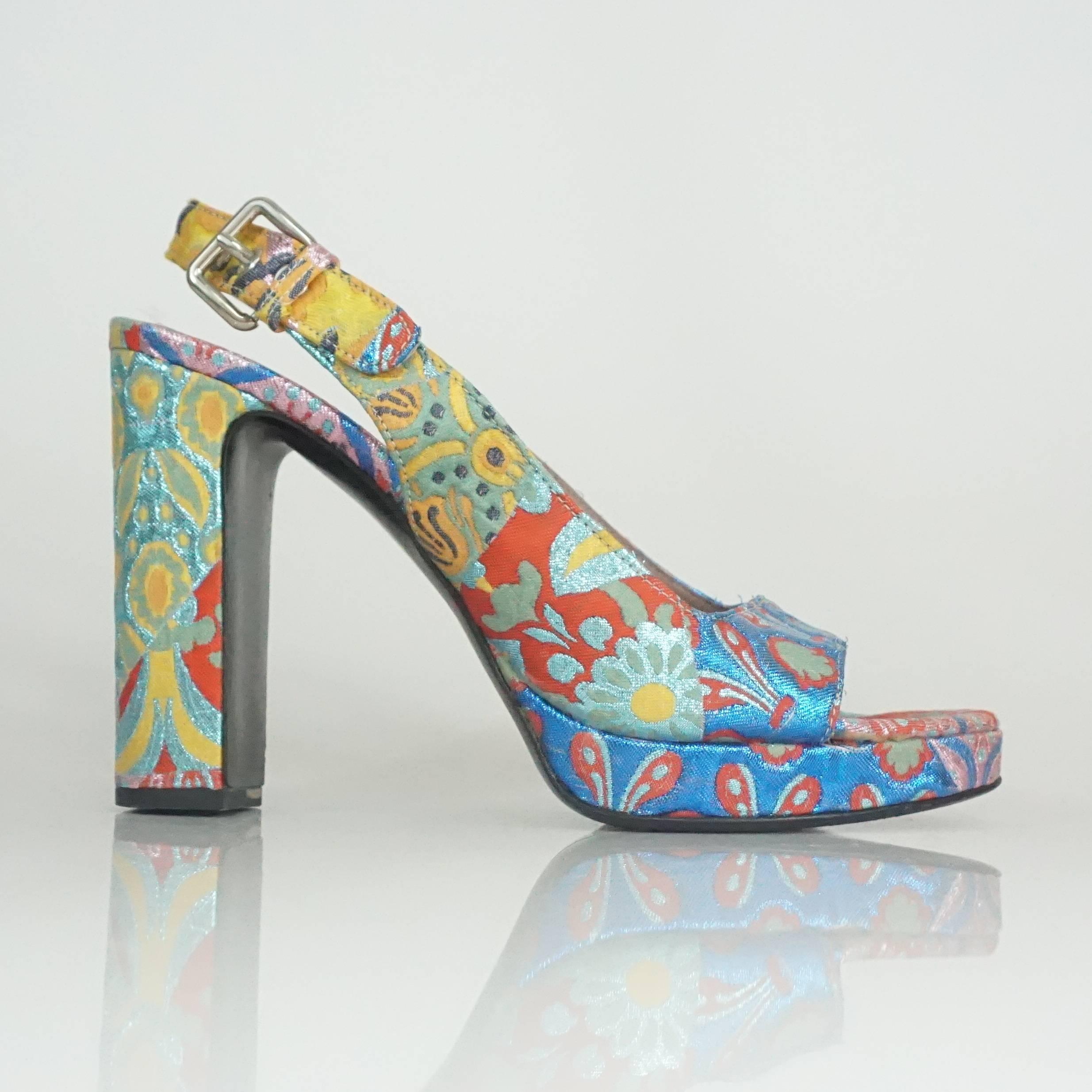 Miu Miu Multi Colored Patterned Brocade Open Toe Slingback - 40.5 - SHW. These fun shoes have a chunky heel and multiple colors such as blue, yellow, and coral done in a metallic brocade fabric. The slingback strap has a silver buckle. They are in