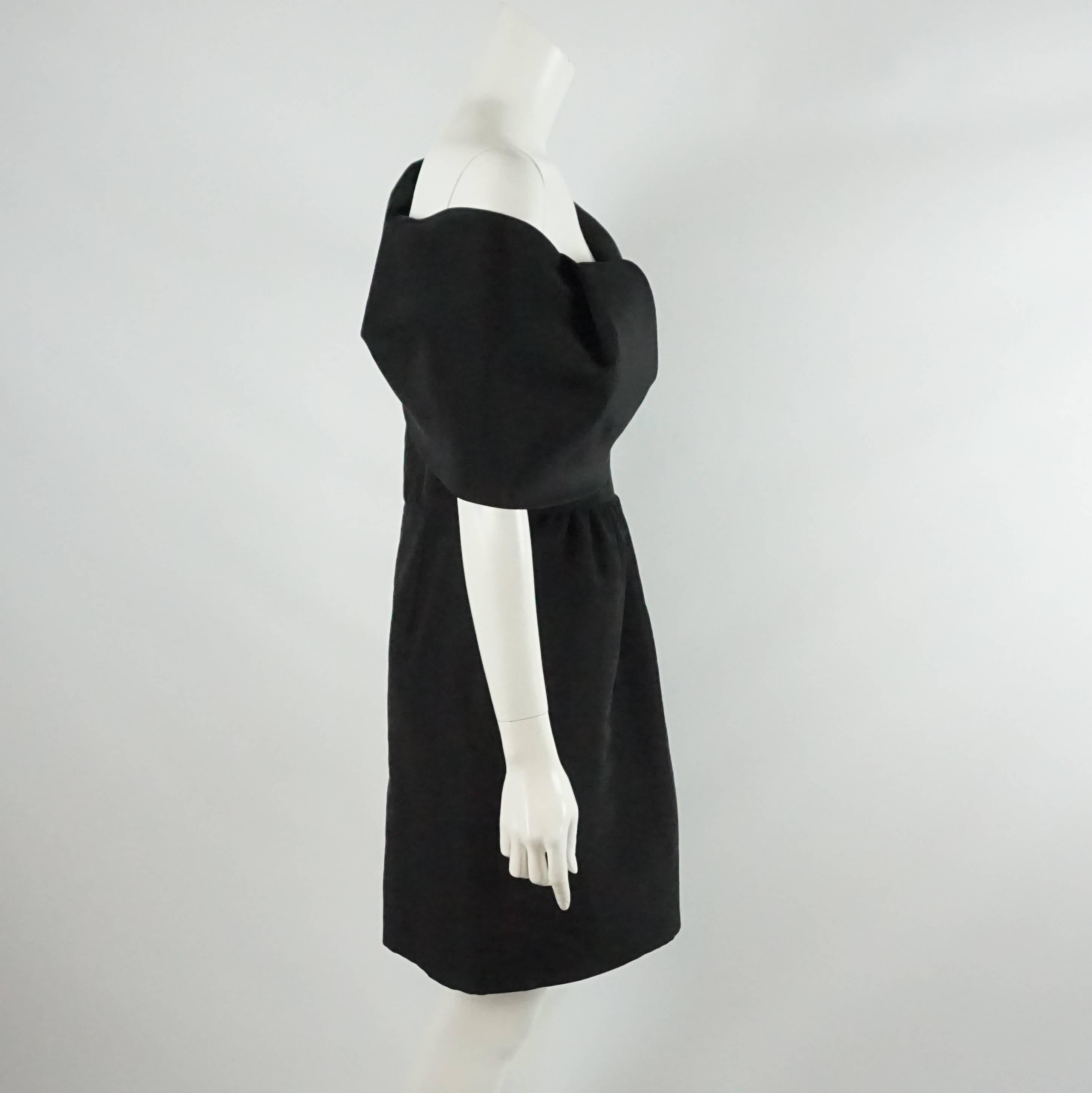 This gorgeous black Oscar dress is made of silk taffeta. It has a one shoulder/over the shoulder neckline with a collar that has a folded over look. The dress is slightly gathered at the waist flowing into the skirt. It is a size 10 and in excellent