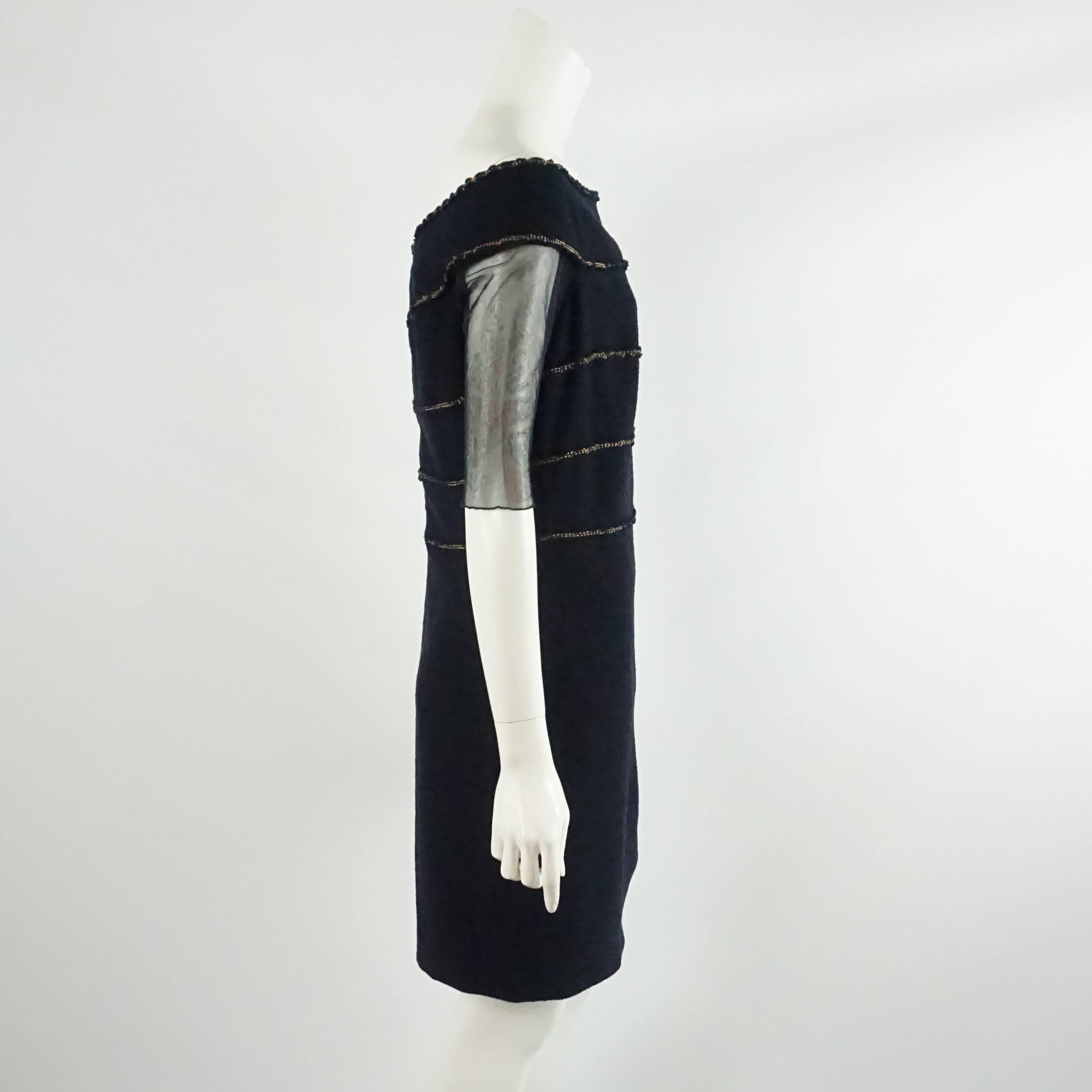 This Chanel navy wool dress has gold threaded detail on the bodice and slight ruching on the left hip. The dress has a boat neck and elbow length mesh sleeves. It is excellent condition with light wear to the wool.

Measurements
Bust: 38