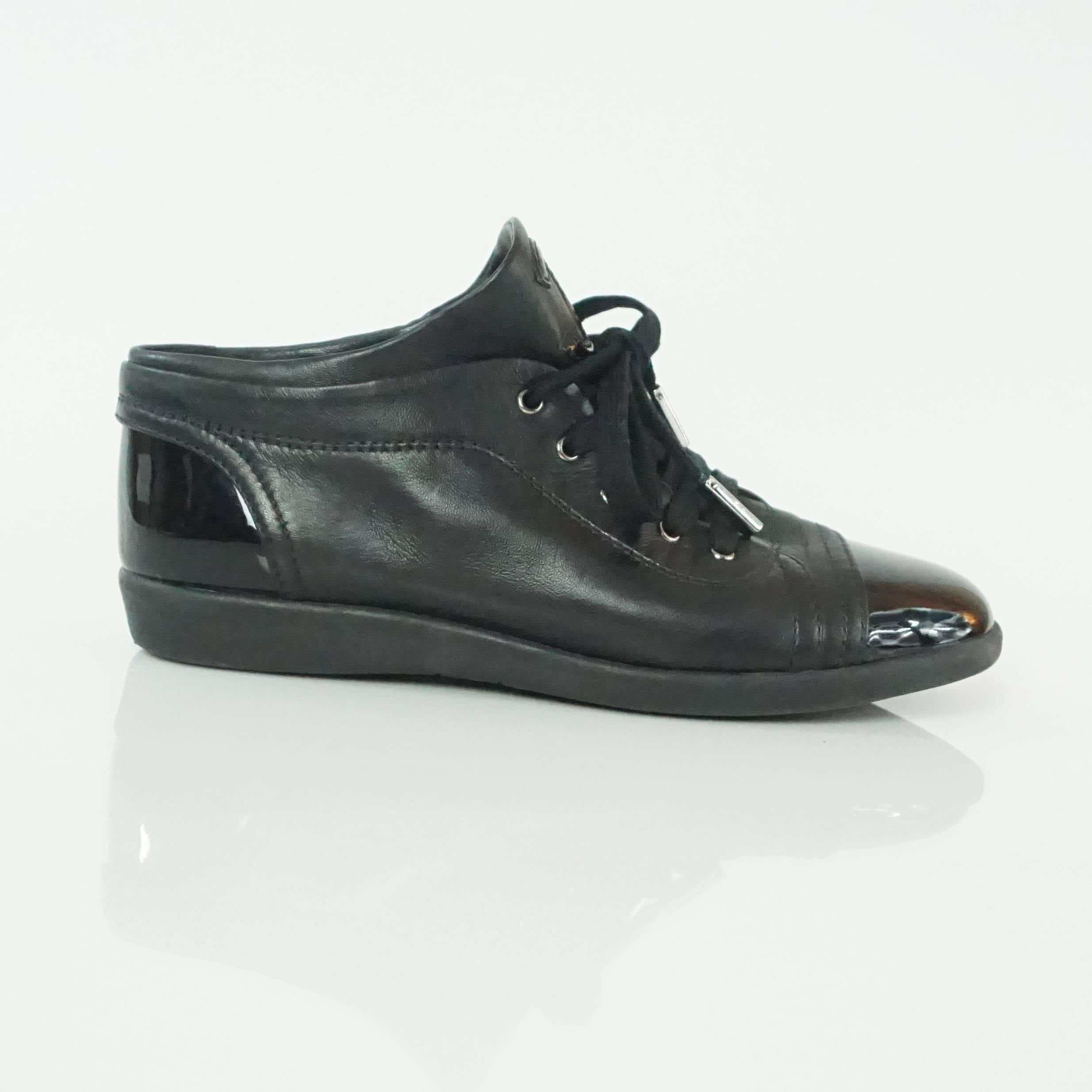 Chanel Black Lambskin and Patent Cap Toe Sneakers - 37.5. These sneakers are in excellent condition with a lambkin body with patent detailing on the front and back. It also has a patent 