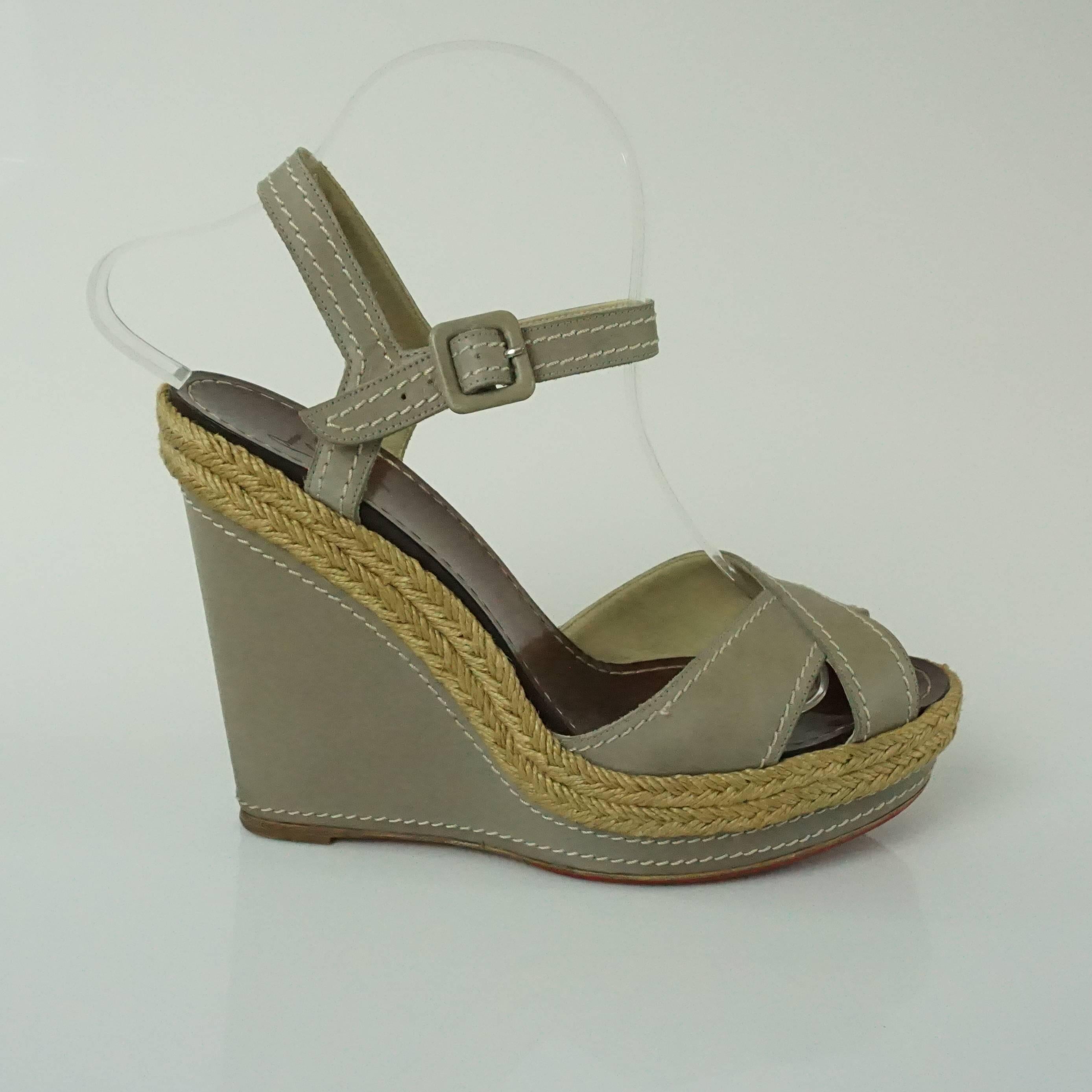 These Louboutin taupe leather wedges have a straw trim on the bottom and ankle strap. They have an open toe with crossing leather straps. The shoes are in good condition with light marks on the wedge and some small stains as seen in the images.