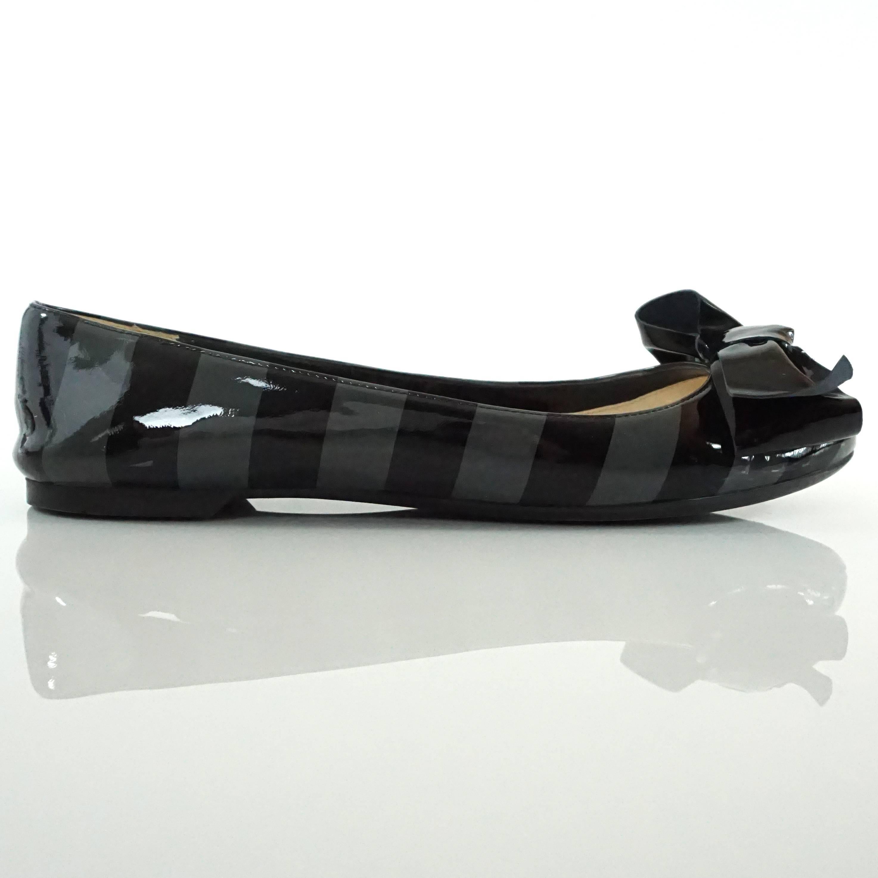 These Prada patent flats have black and gray stripes and a black bow. They come with a duster. These shows are in very good condition with minor wear inside and on the bottom.