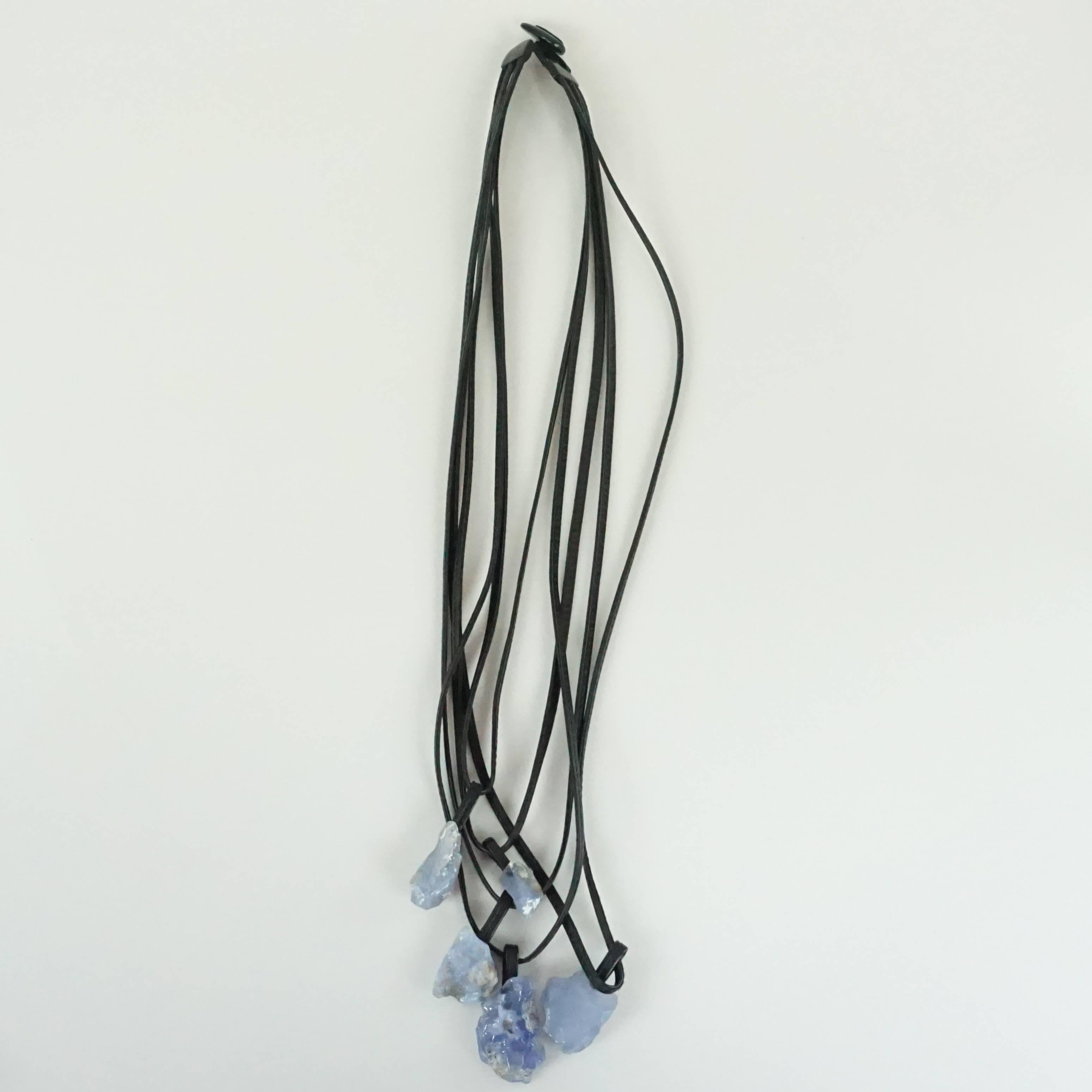 This Monies long necklace is composed of several leather cords with different lengths that have blue chalcedony stones at the end. The necklace is in excellent condition with minimal wear. There are also matching Chalcedony earrings available,