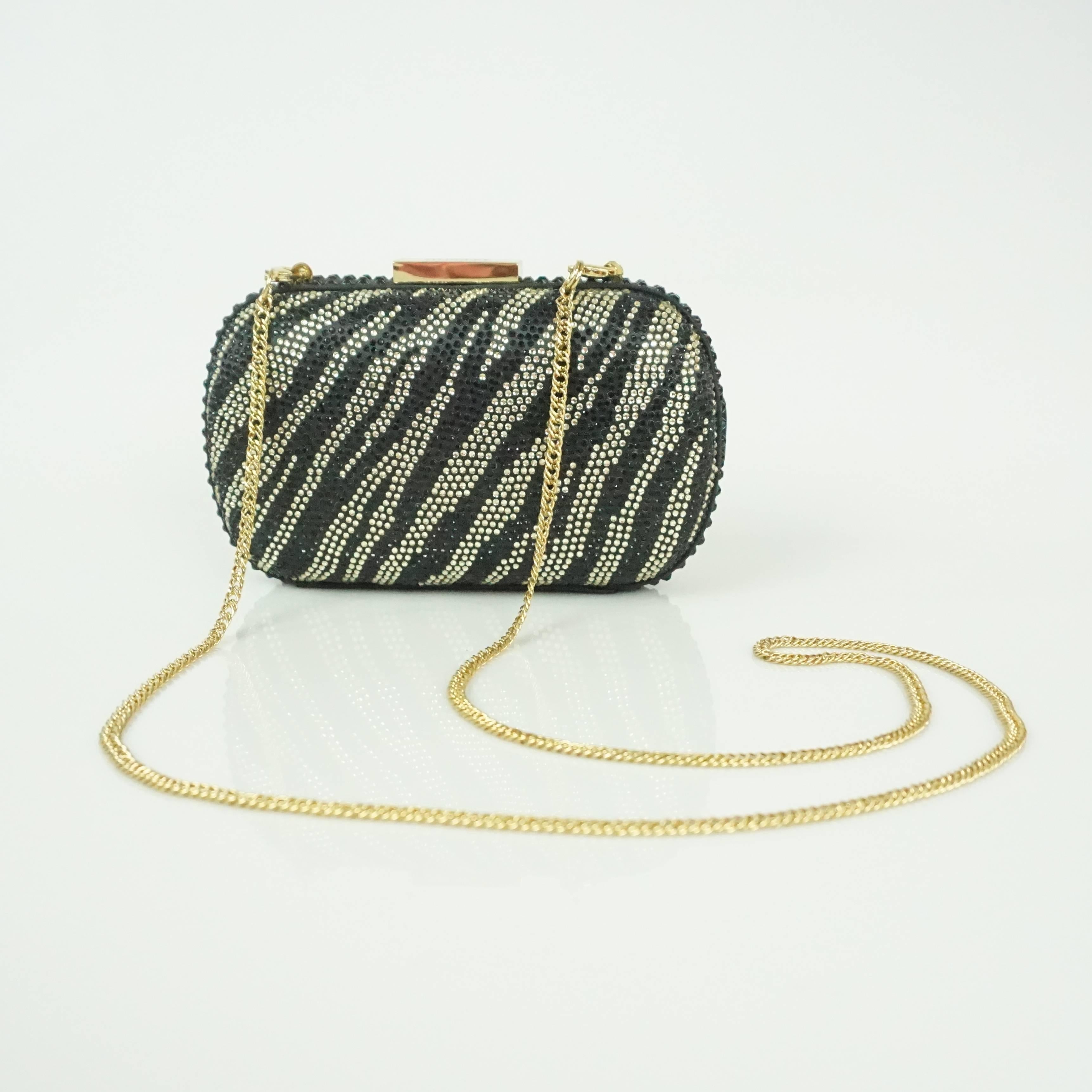 This Badgley Mischka clutch is covered in black and light gold rhinestones. These rhinestones form a somewhat zebra print and there is a removable gold chain. Inside, there is a small pocket. This clutch is in excellent