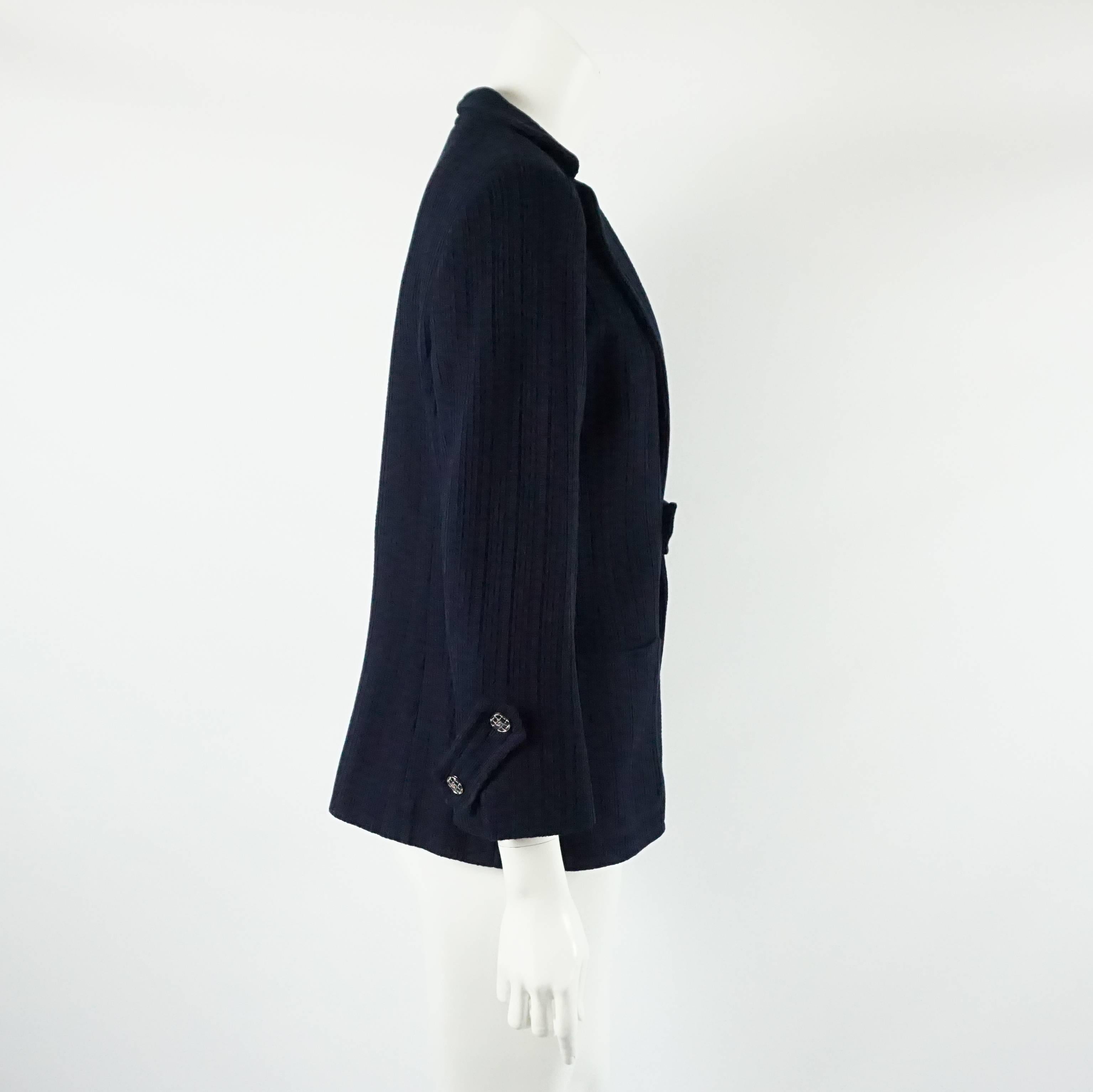 This Chanel navy cotton jacket has an open style with a strip of fabric in the center acting as a closure. It has silver and navy enamel buttons with center 
