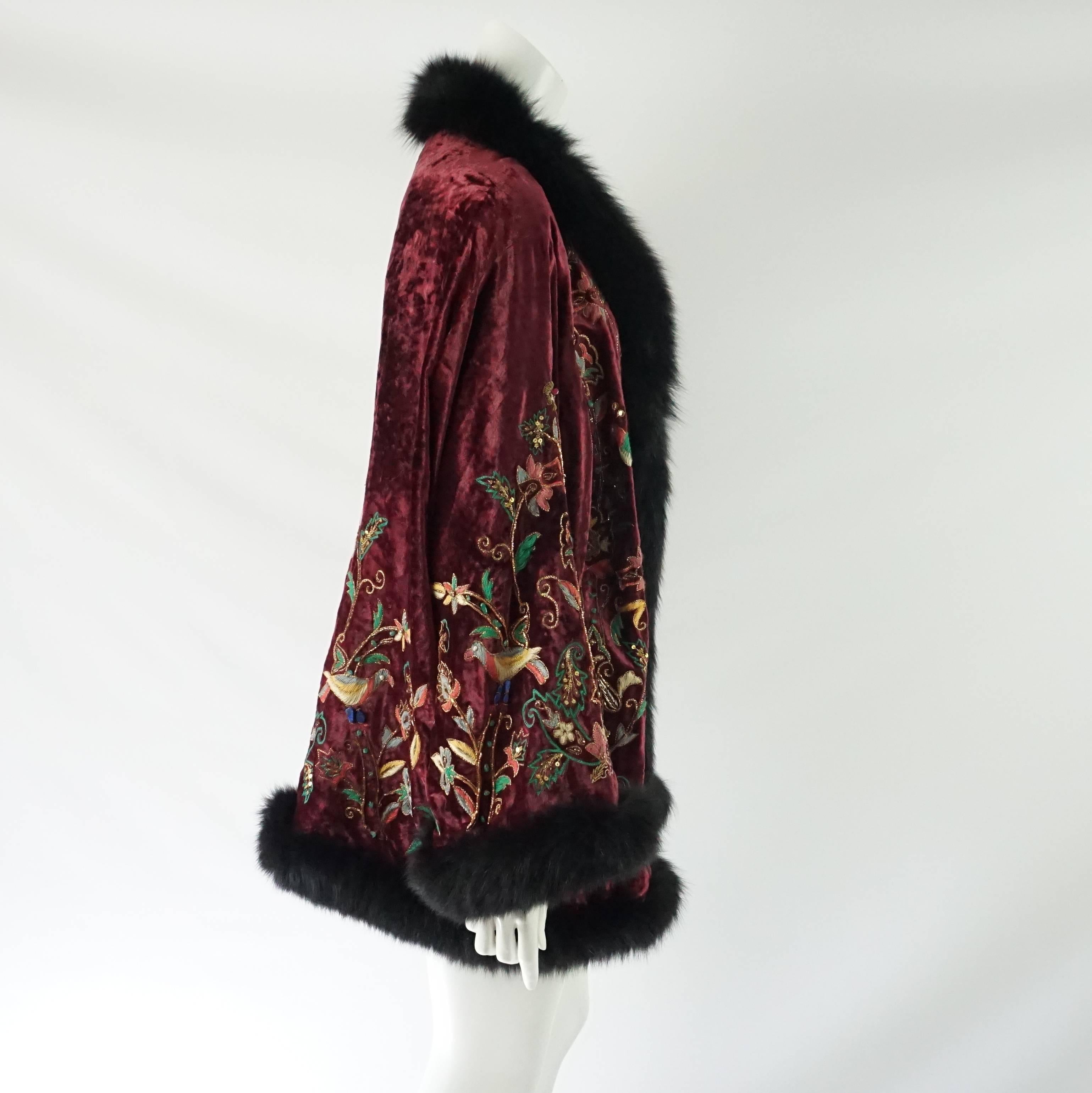 This luxurious Adrienne Landau cape is made of red velvet and has a fox fur trim. There is intricate embroidery in multiple colors throughout the coat. This piece is in excellent condition with minor wear. 

Measurements
Shoulder to Shoulder: