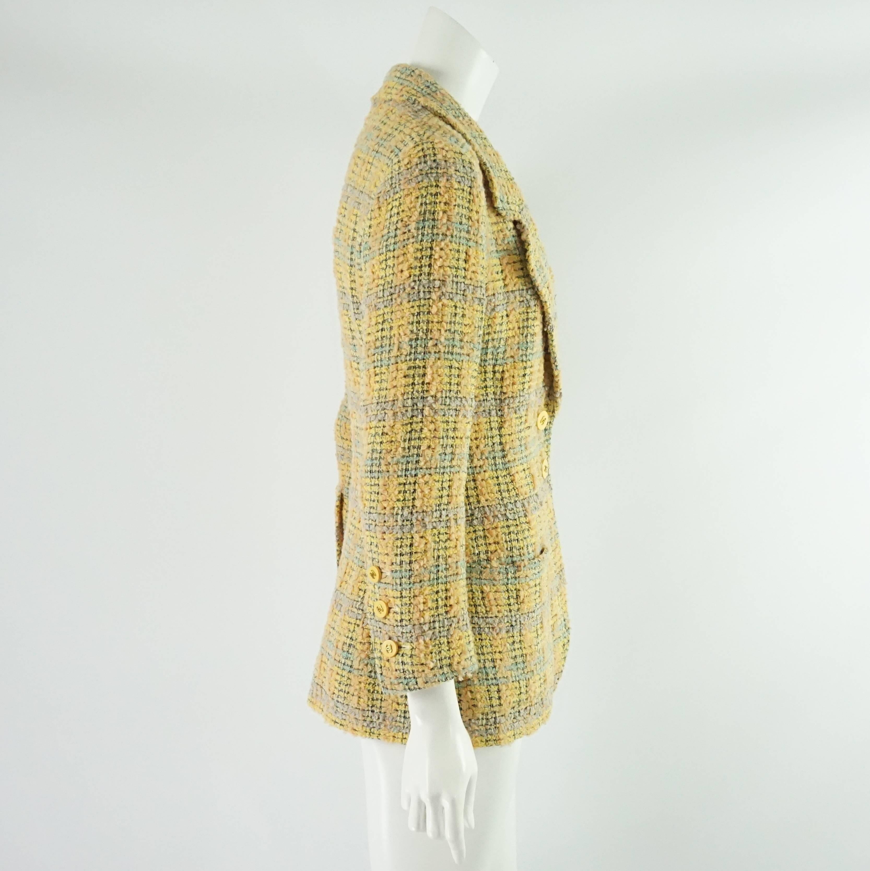 This beautiful Chanel jacket is yellow and peach plaid tweed in a wool blend. The buttons are a yellow enamel with gold CC's in the center. The front of the piece has 3 pockets and 2 buttons. The jacket is in excellent condition with light wear.