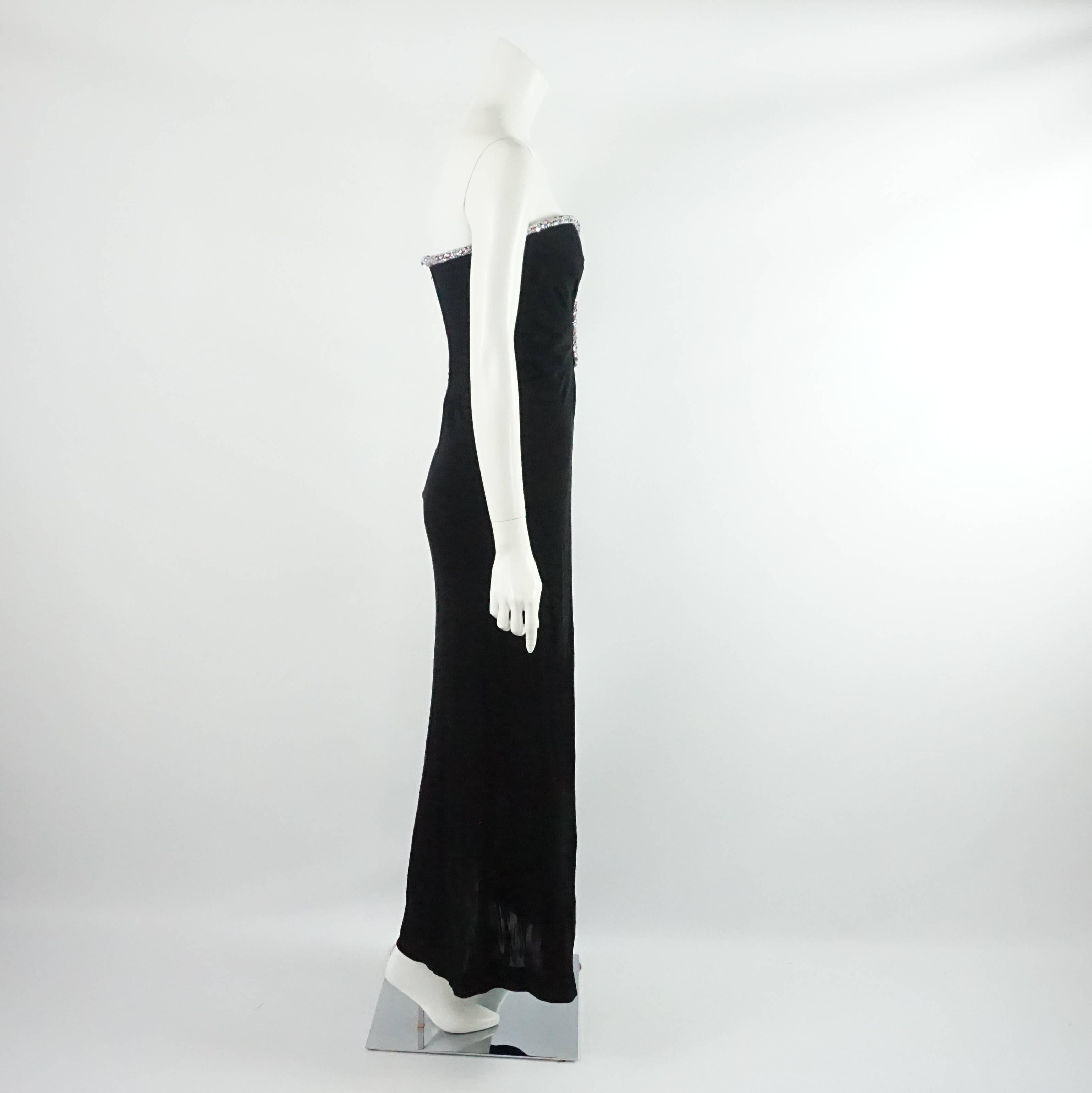 This Bob Mackie black gown is strapless with a sweet heart neckline. It has a keyhole near the bust and a trim in clear, pink, and blue rhinestones. The inside also has boning along the bodice. The gown is in good vintage condition with some wear to