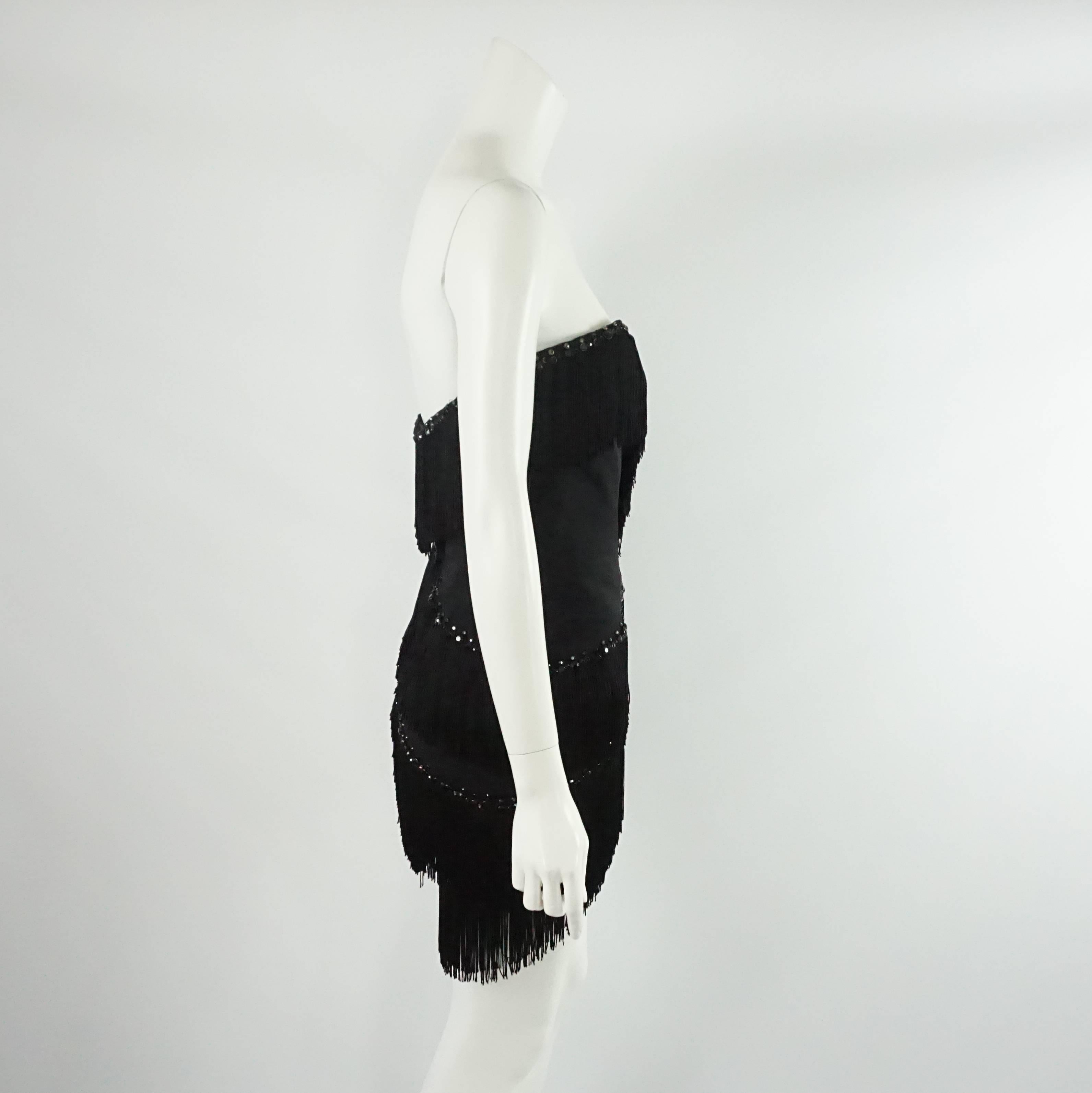 This Bob Mackie vintage dress has a sweet heart neckline and is short with fringes and black rhinestones all over. The dress zips in the back and has boning all along the inside. It is in excellent vintage condition with light wear to the