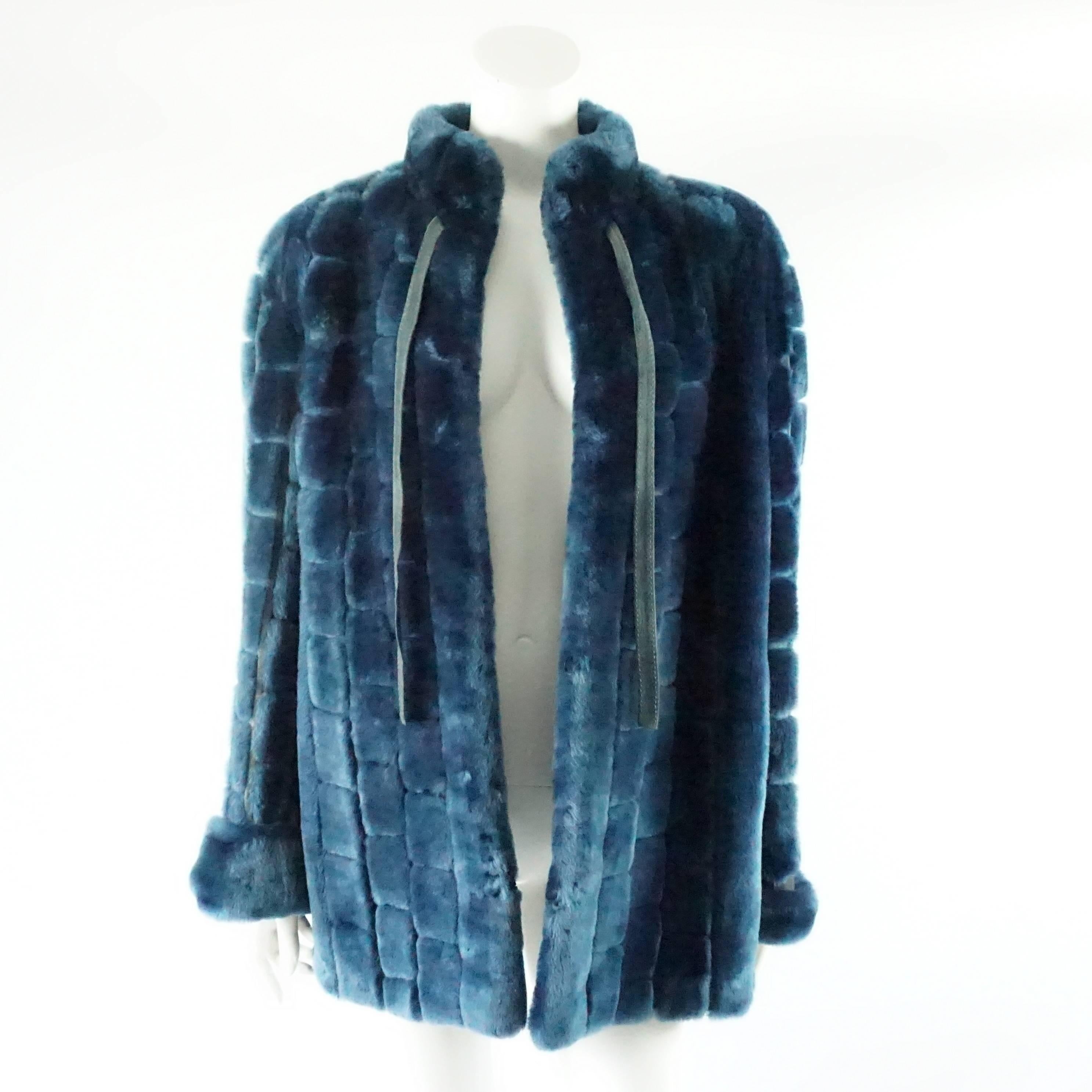 This vintage Dior blue faux fur coat has 2 front ties and hook and eye closures. The coat has square fur sections with suede in between. This coat is in fair vintage condition with some staining on the suede and some of the lining by the armpit is