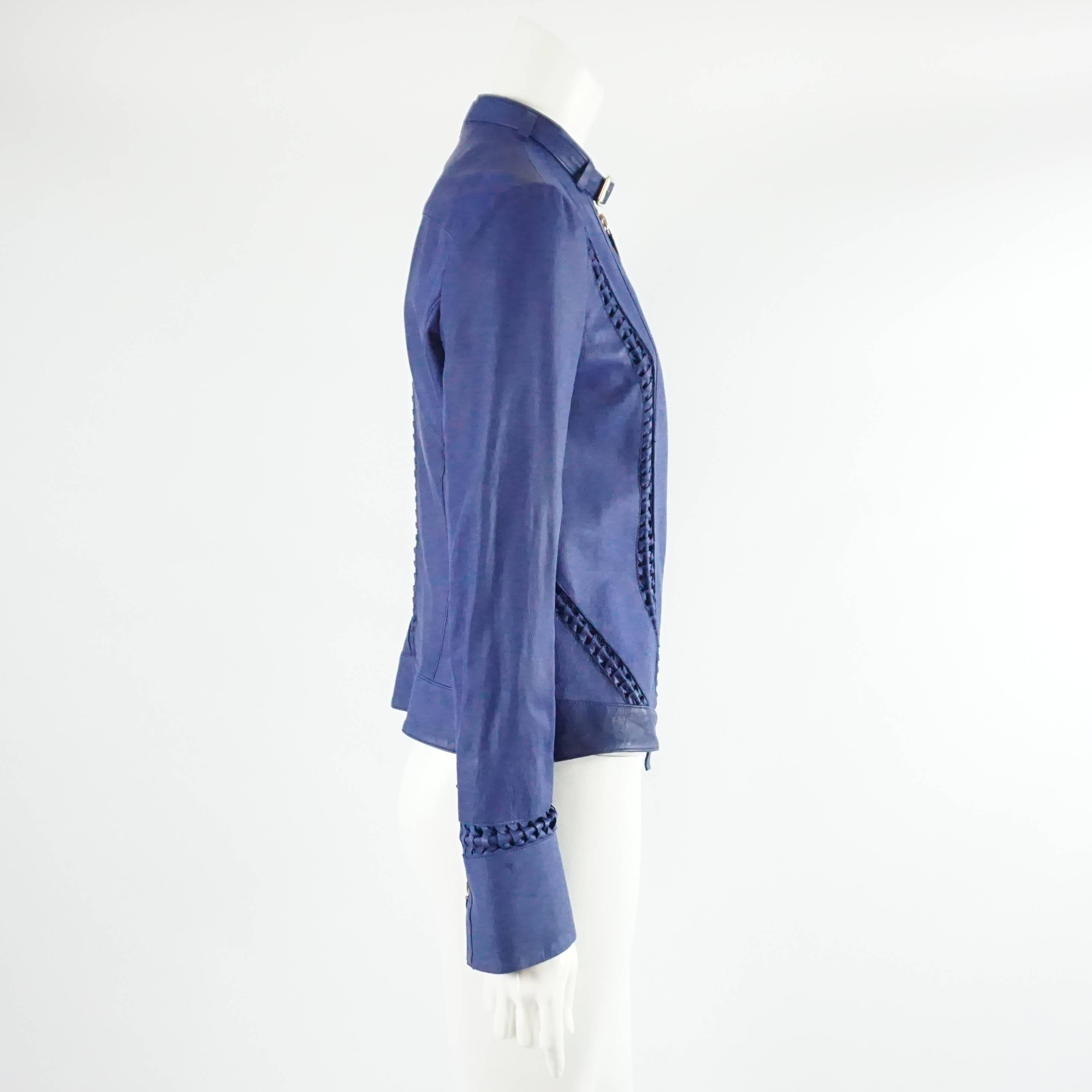 This Roberto Cavalli leather jacket is blue with a silver zipper (there are two zipper pulls) and buckle around the neck. On the back of the cuffs there is a zipper. The front, side, and back have braided detail. This jacket is in good condition